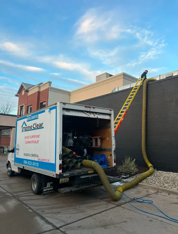 A white truck with the back door open is parked in front of a building.