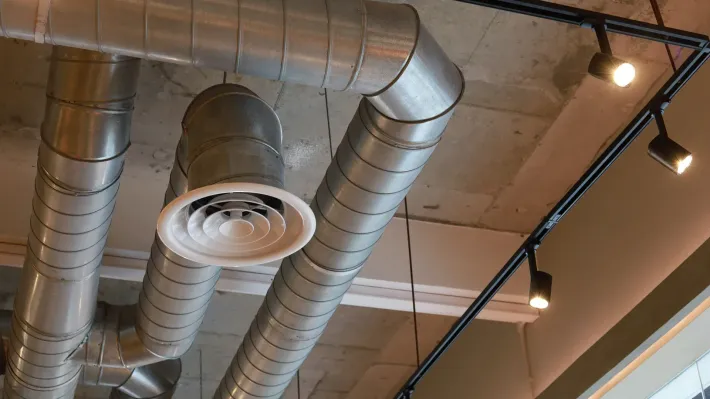 A bunch of metal pipes are hanging from the ceiling of a building.