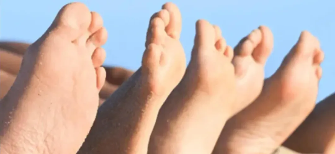 A group of people 's feet are lined up in a row against a blue sky.
