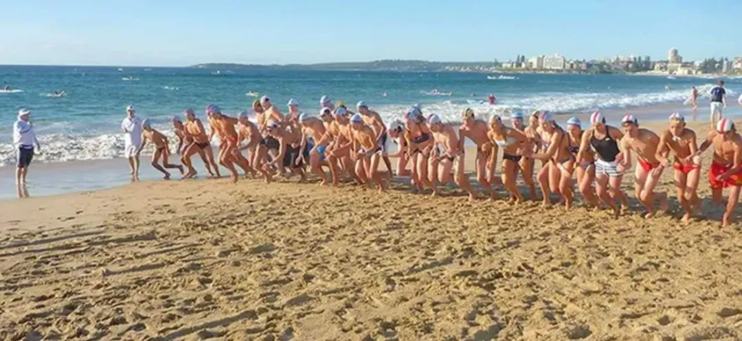A group of people are running on a beach near the ocean.