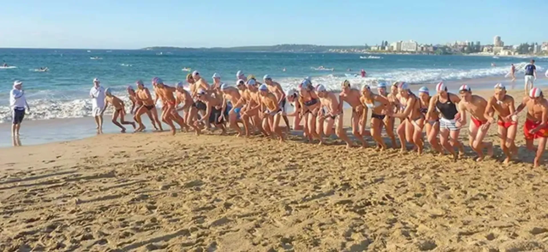 A group of people are running on a beach near the ocean.