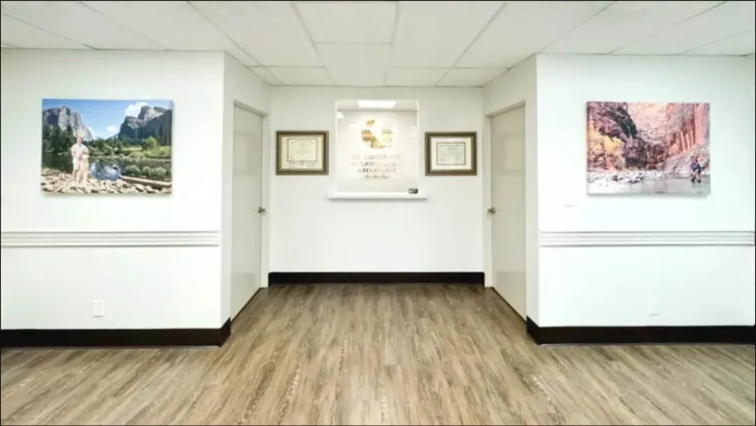 A hallway with a wooden floor and paintings on the wall.