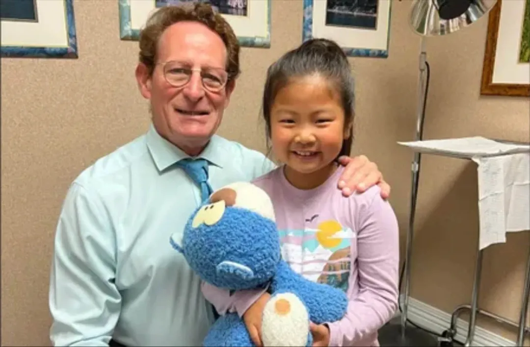 A man and a little girl are holding a stuffed animal.