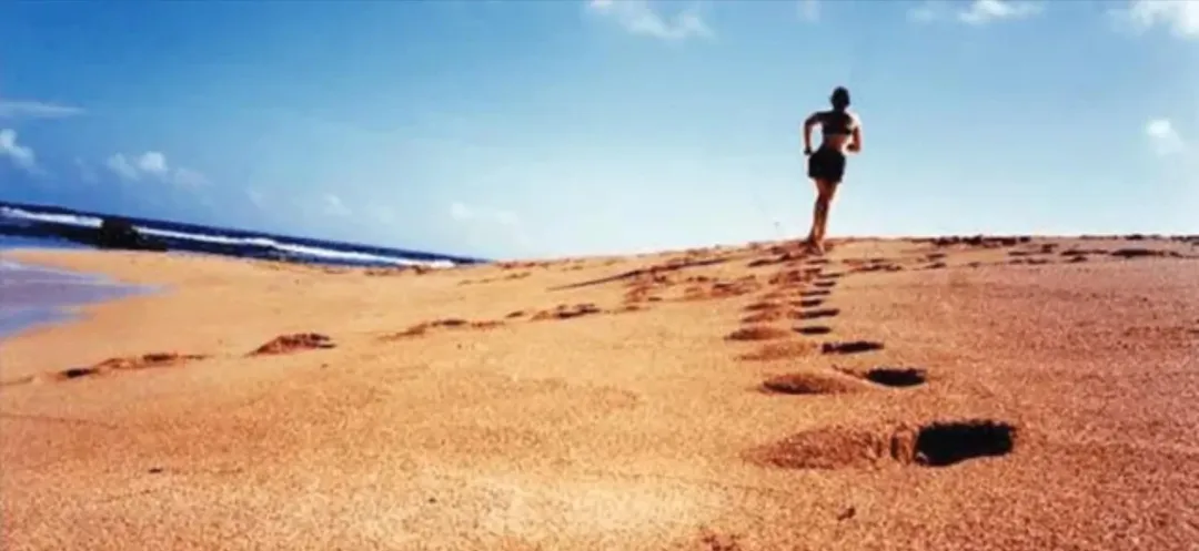 A person is running on a beach leaving footprints in the sand