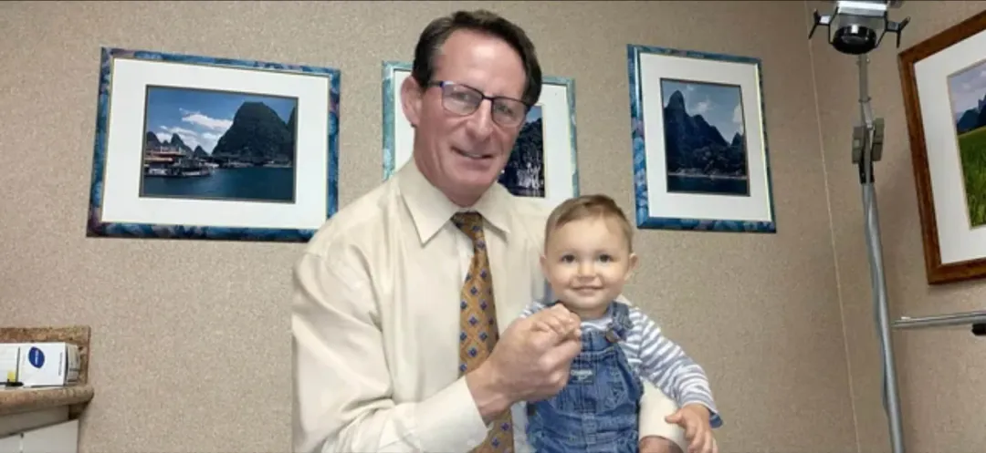 A man in a tie is holding a baby in his arms