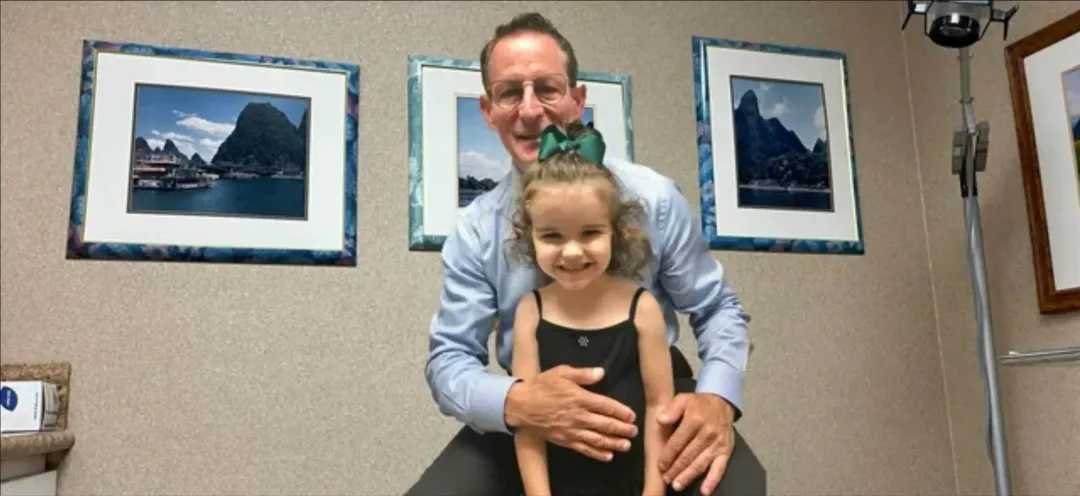 A little girl is sitting on a man 's lap in a doctor 's office.