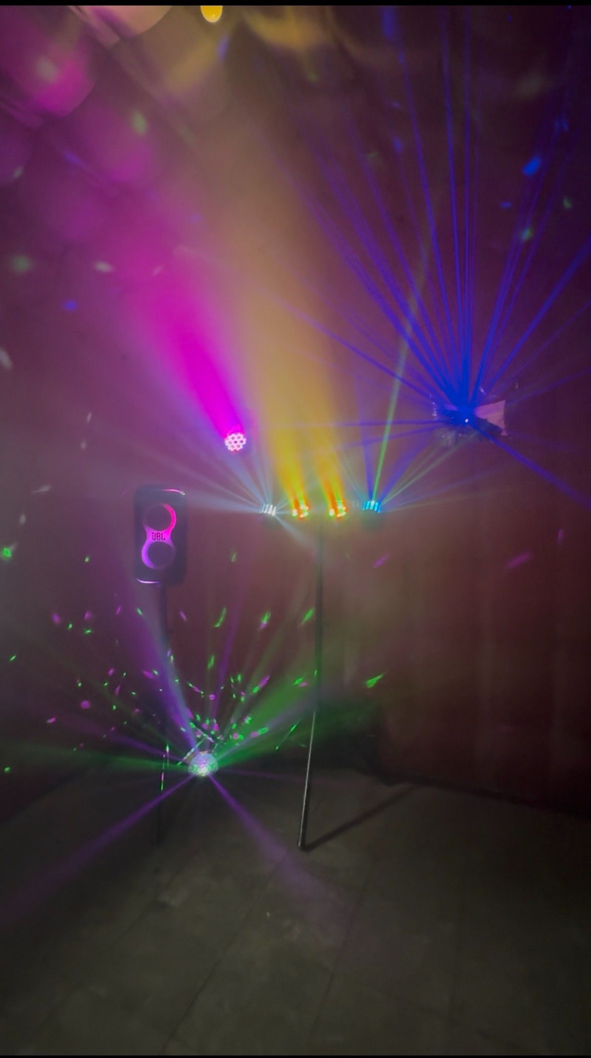 Twee zwarte laserprojectoren die rode, groene en blauwe lichtstralen op een donker oppervlak projecteren.