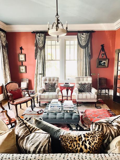 A room with hardwood floors, a vintage mannequin wearing a tweed blazer, and an entryway with columns and ornate furniture.