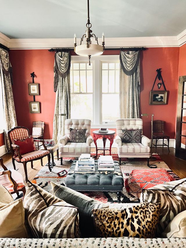 A room with hardwood floors, a vintage mannequin wearing a tweed blazer, and an entryway with columns and ornate furniture.