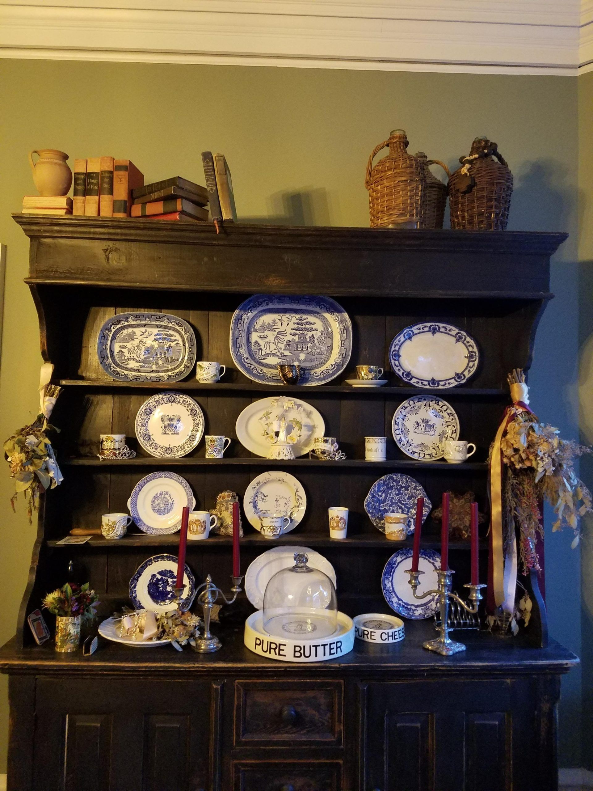 Wooden hutch displaying blue and white china, candles, and decorative items.