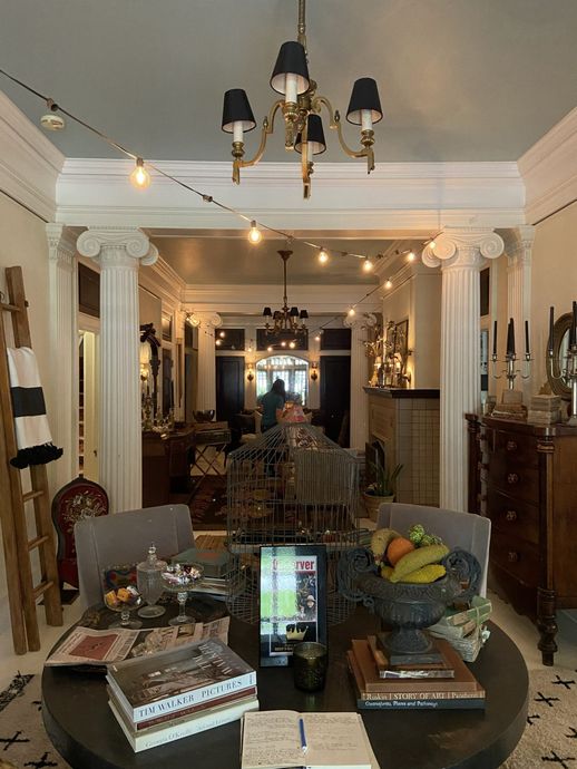 Elegant dining room with chandelier, round table, ornate decor, and a view into connected rooms.