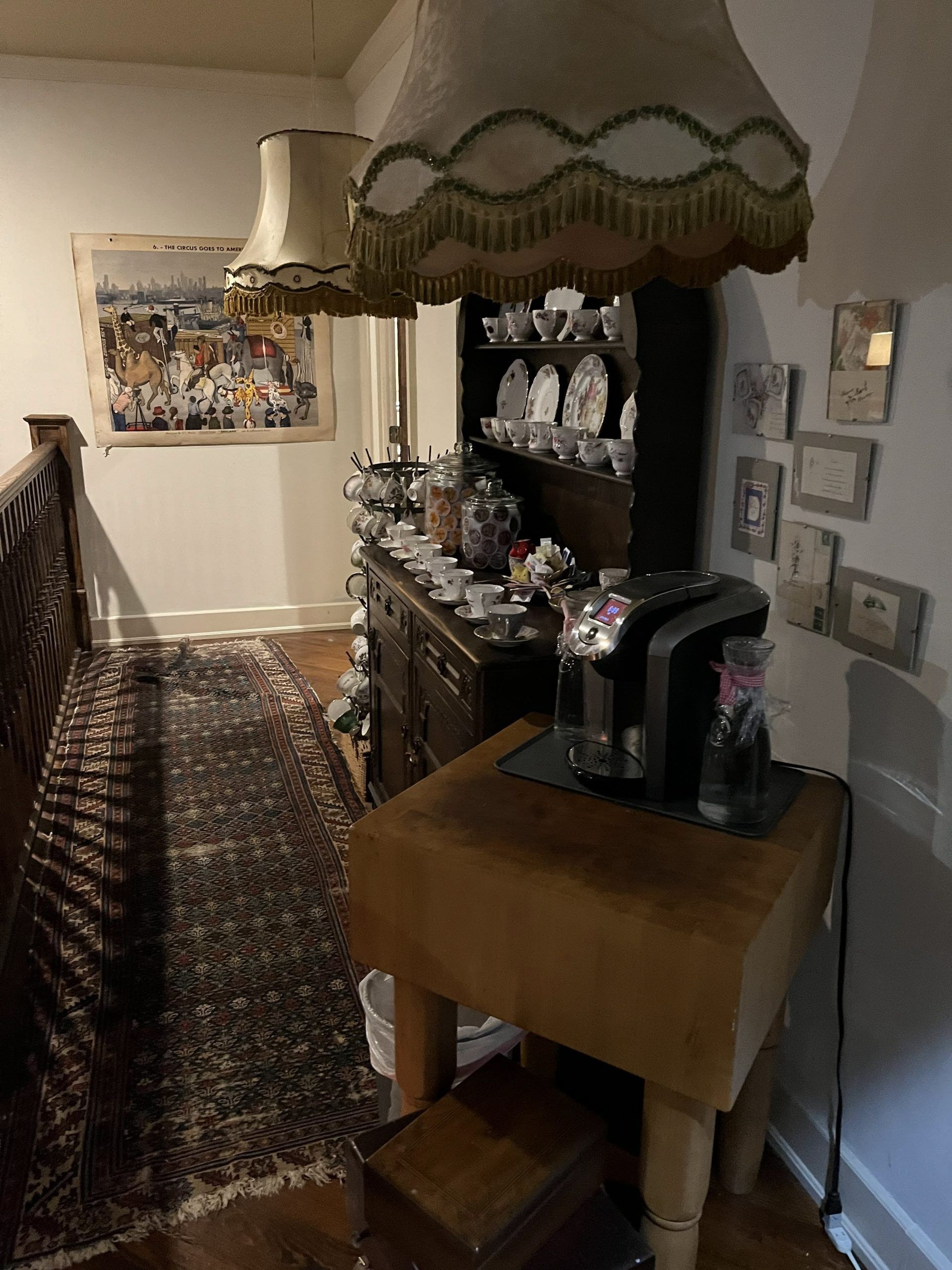 Hallway with ornate furniture, rug, and artwork. A coffee maker sits on a wooden block.