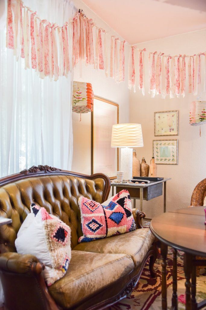 Cozy living room with tufted brown couch, colorful pillows, and decorative paper garland.