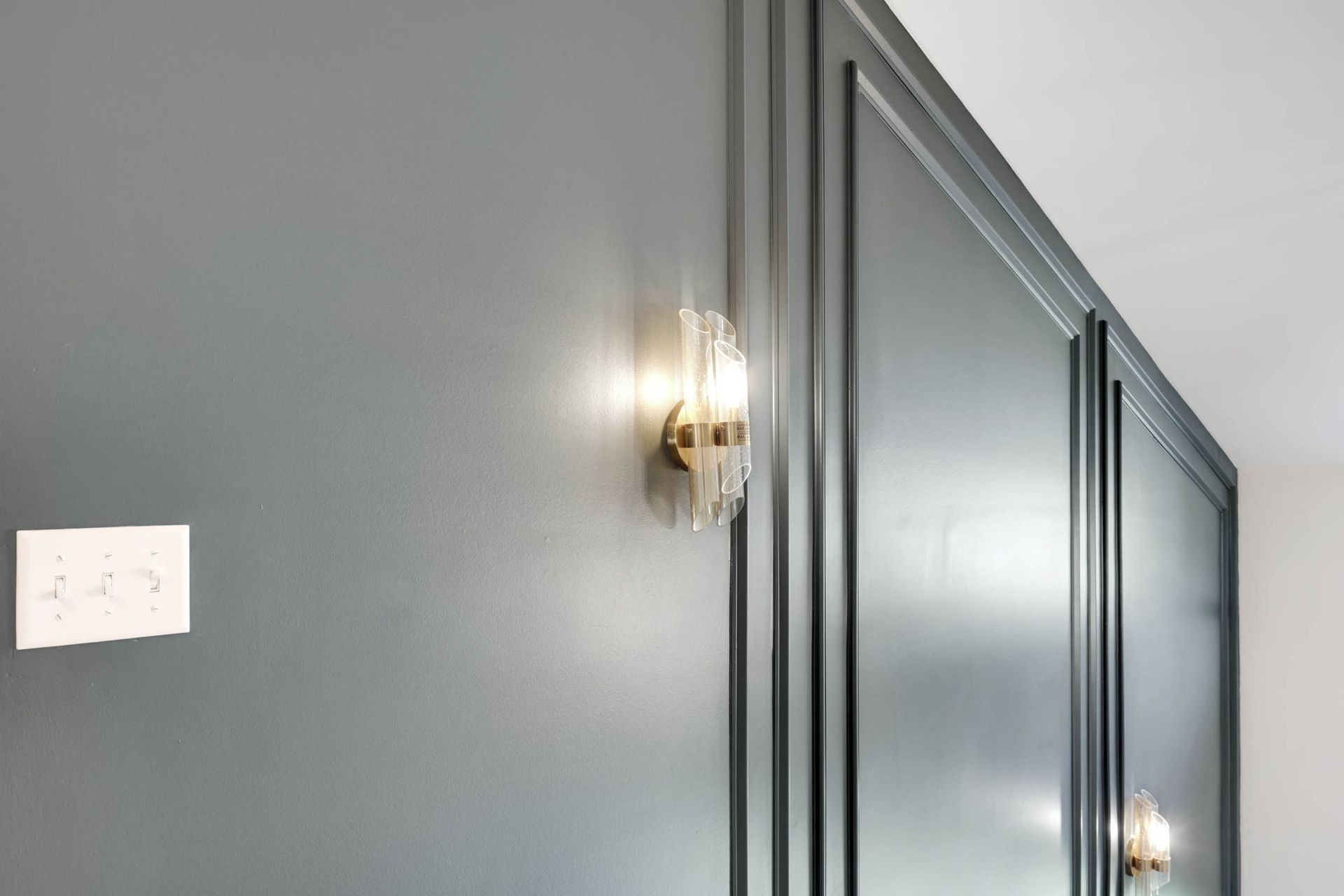 A hallway with a gray wall and a light on the wall.
