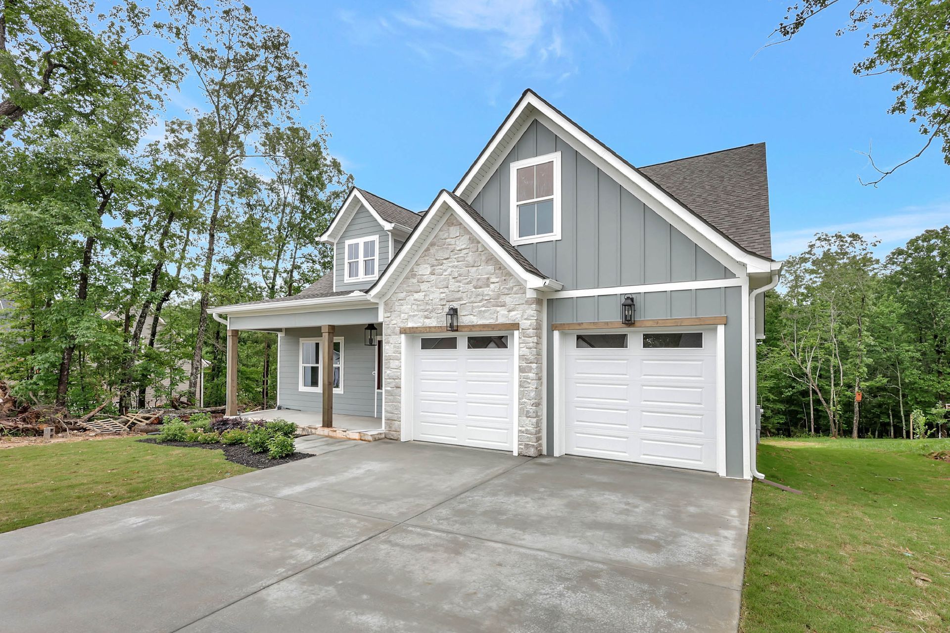 A large gray house with two white garage doors is for sale.