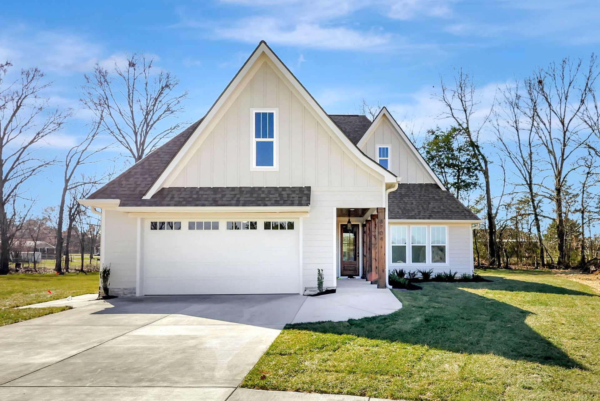 A white house with a black roof and a white garage door.