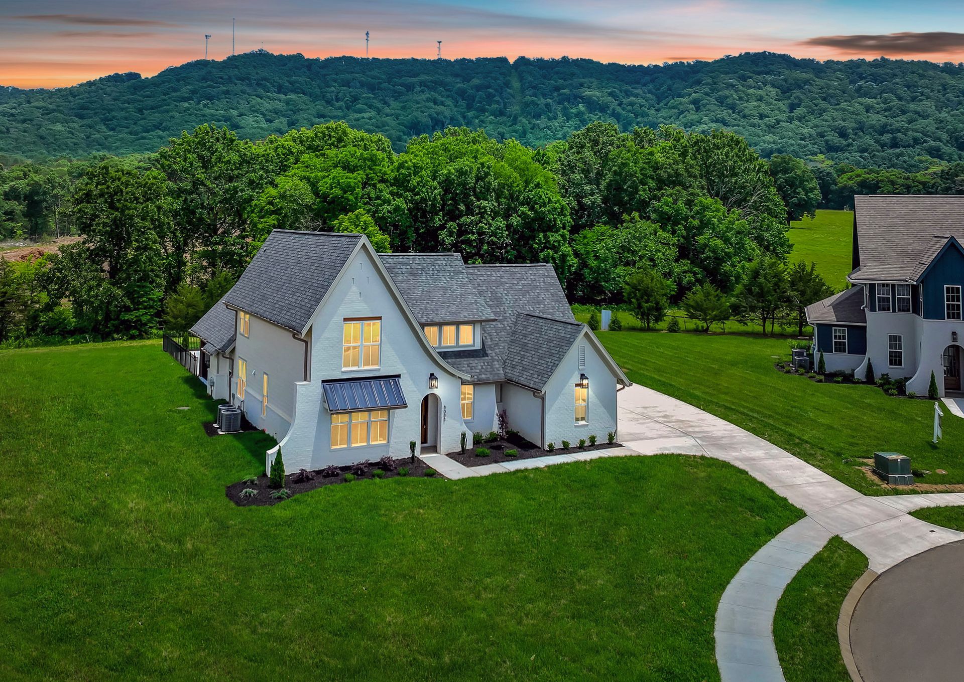 An aerial view of a white house sitting on top of a lush green hillside.