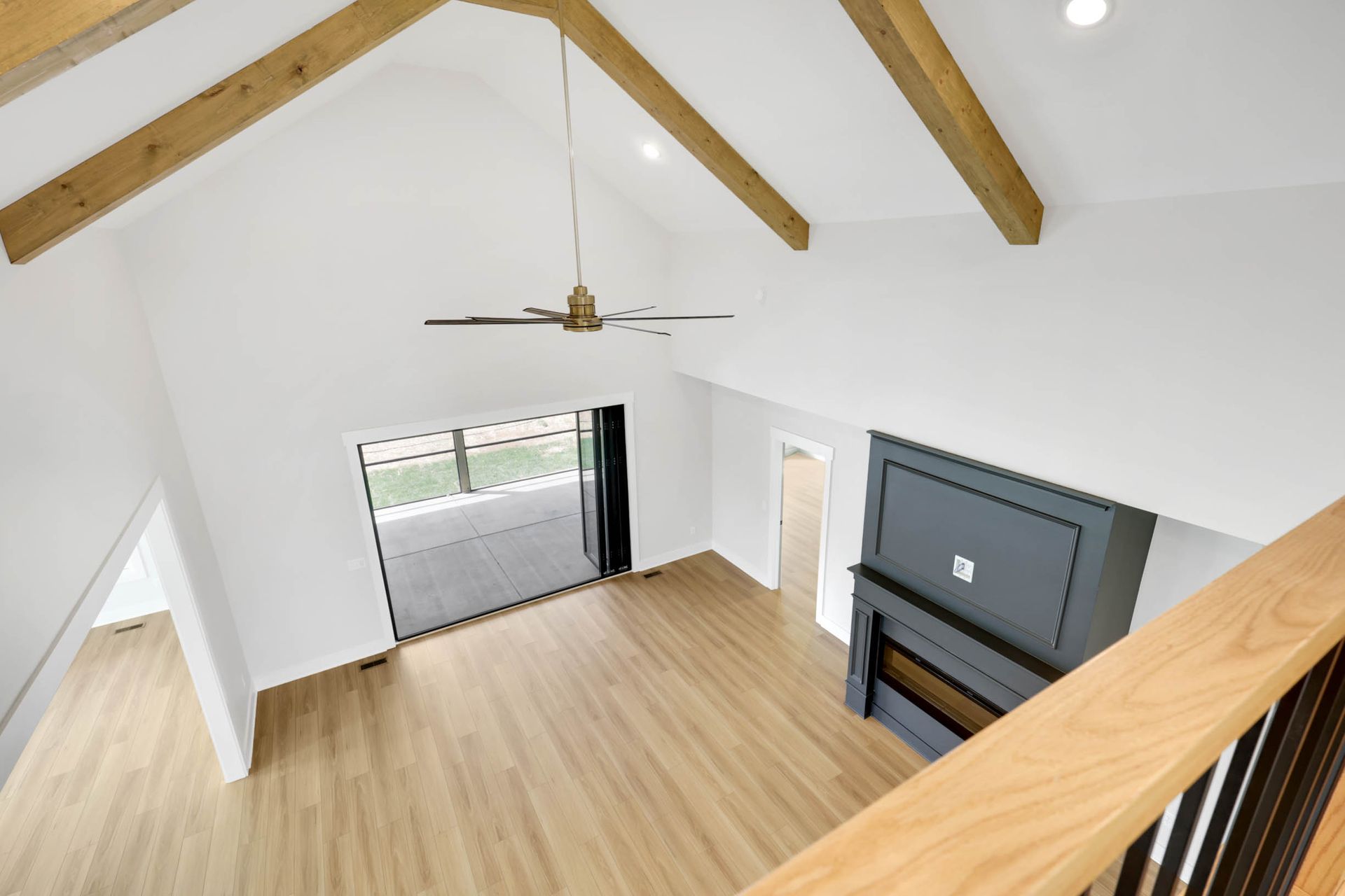An aerial view of an empty living room with a fireplace and ceiling fan.