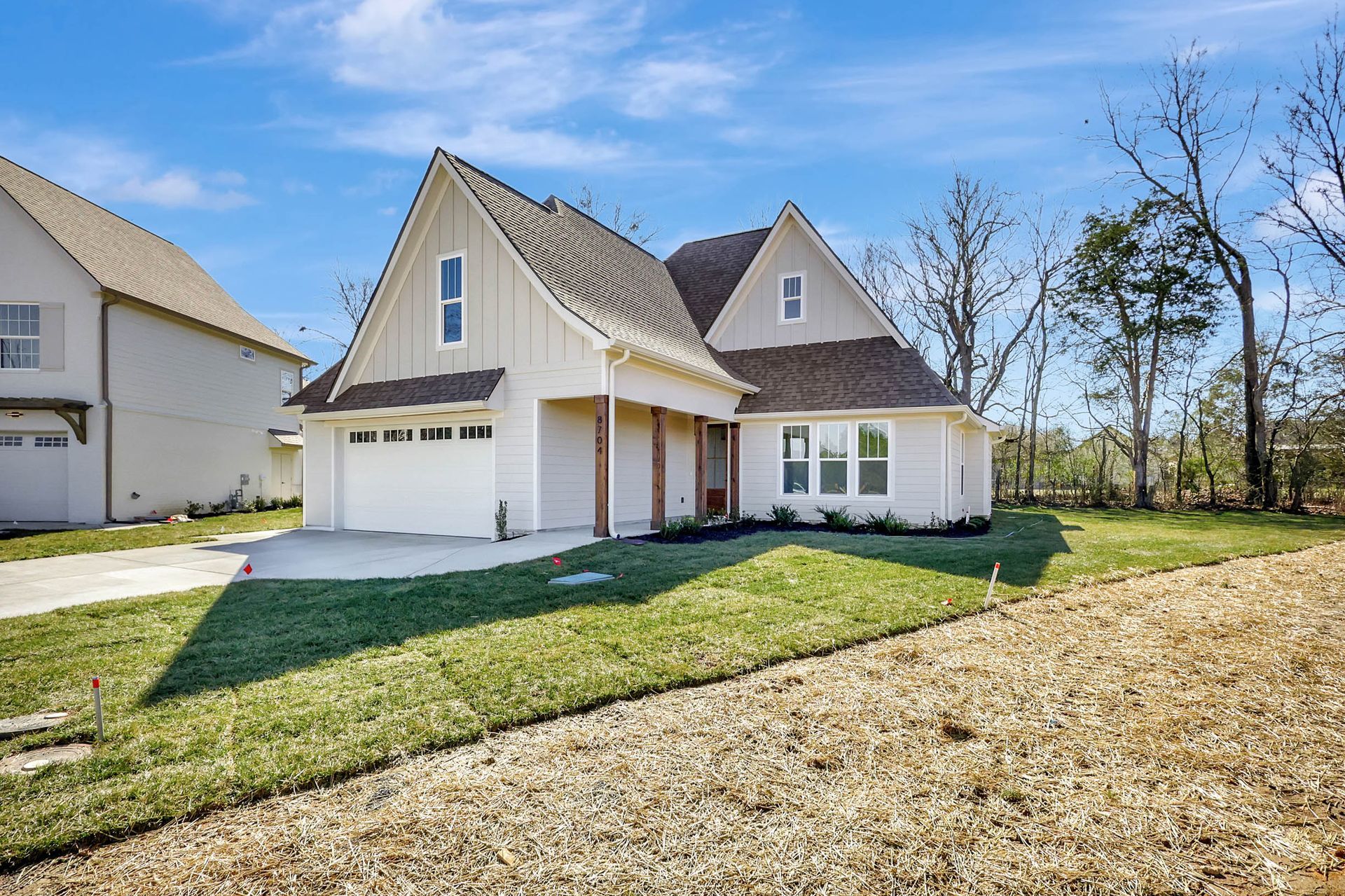 A white house with a brown roof is sitting on top of a lush green field.