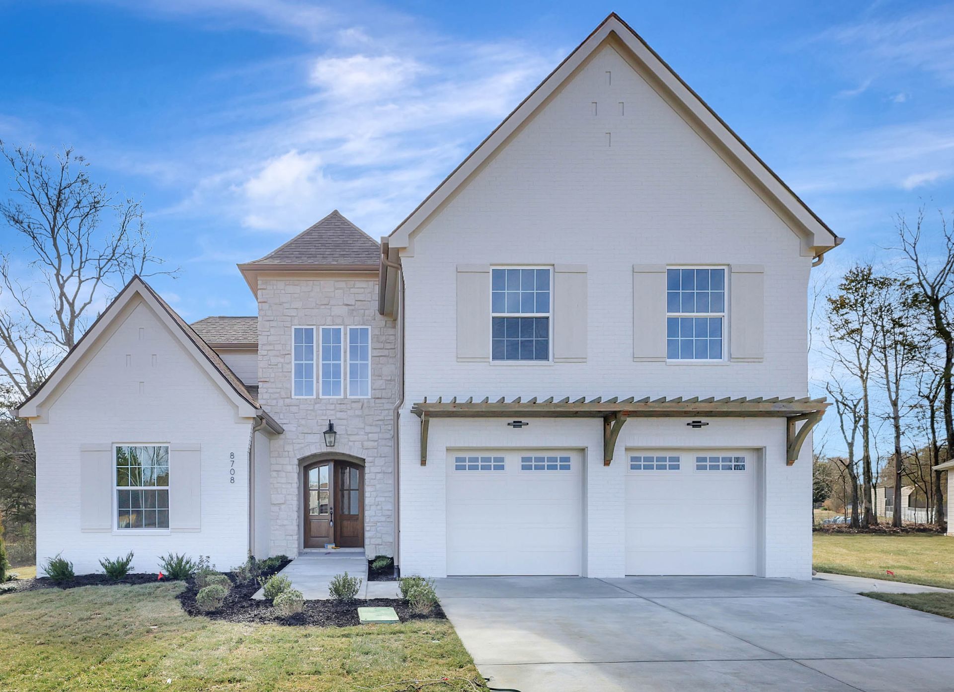 A white house with two garage doors and a brick roof