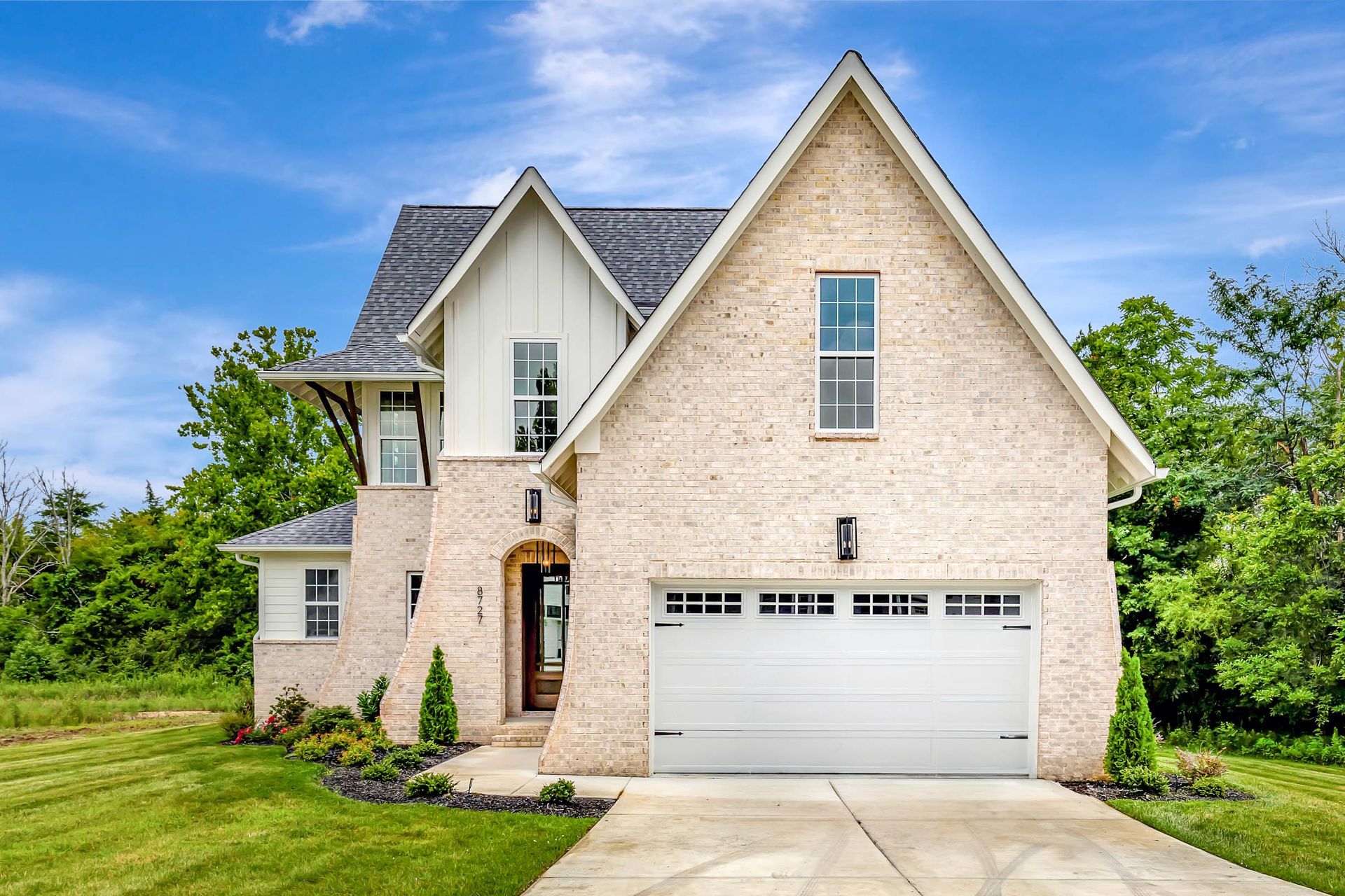 A large brick house with a white garage door and a driveway.