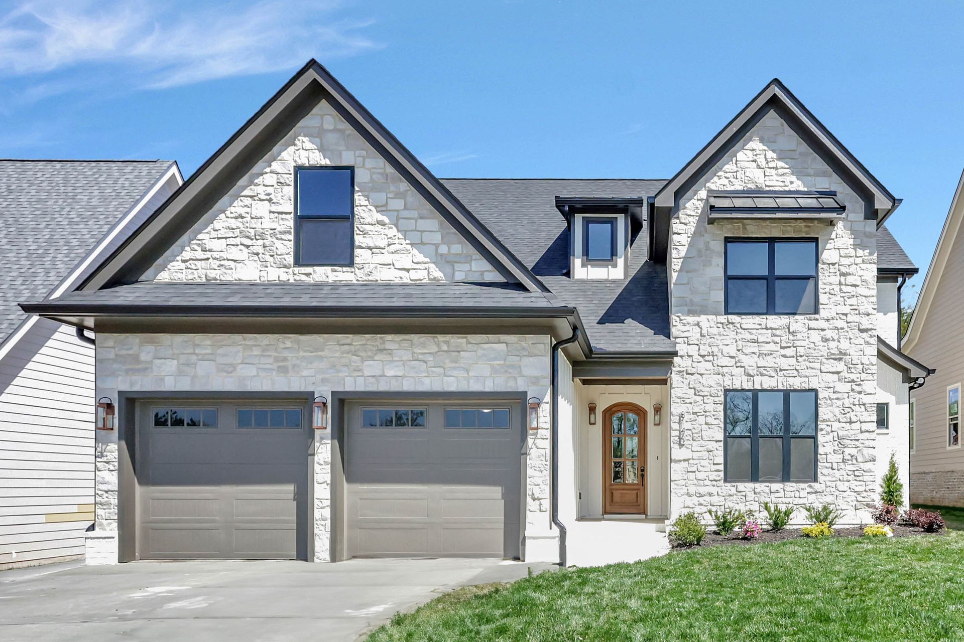 A large brick house with two garage doors and a gray roof