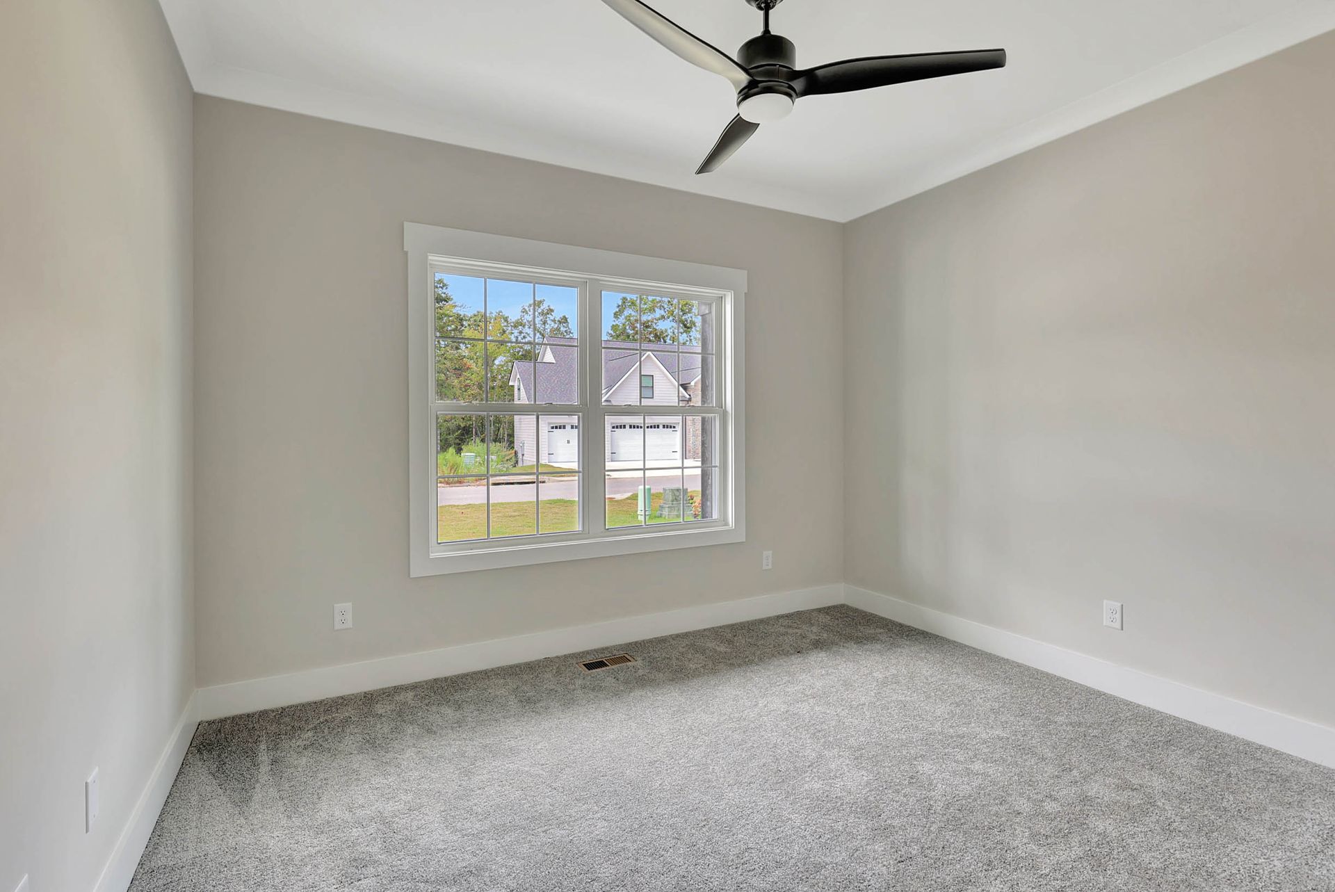 An empty bedroom with a ceiling fan and a window.