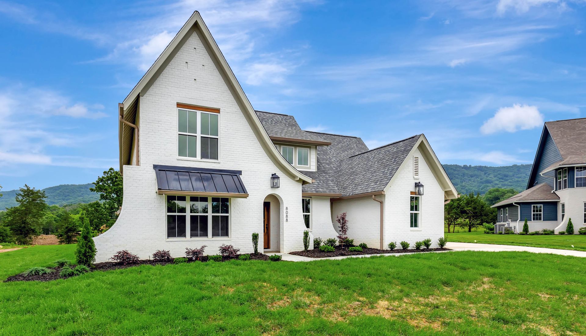 A large white house is sitting on top of a lush green field.