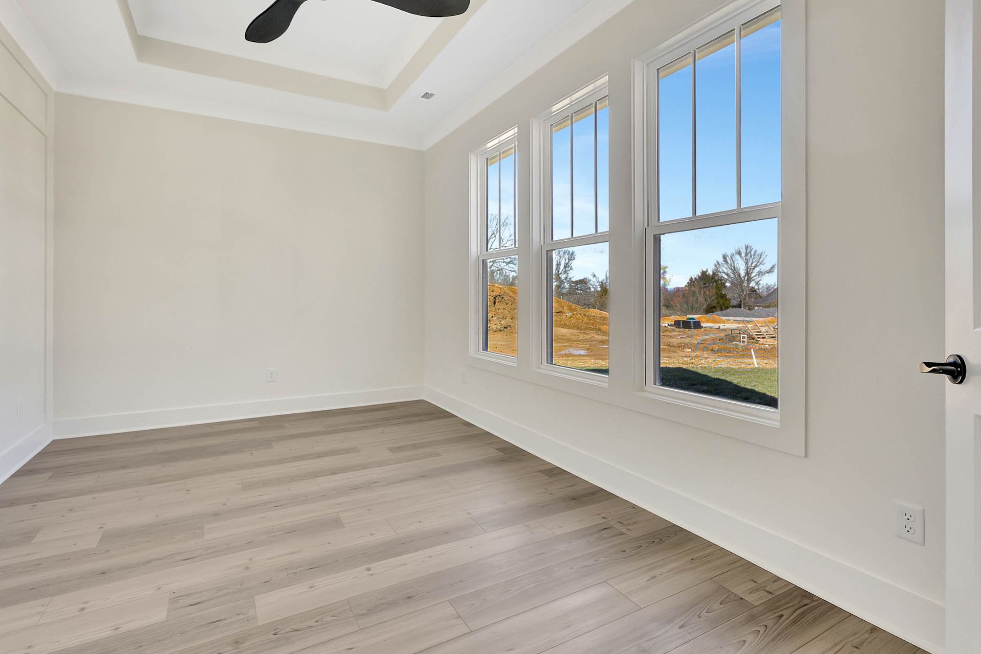 An empty room with hardwood floors and a ceiling fan.