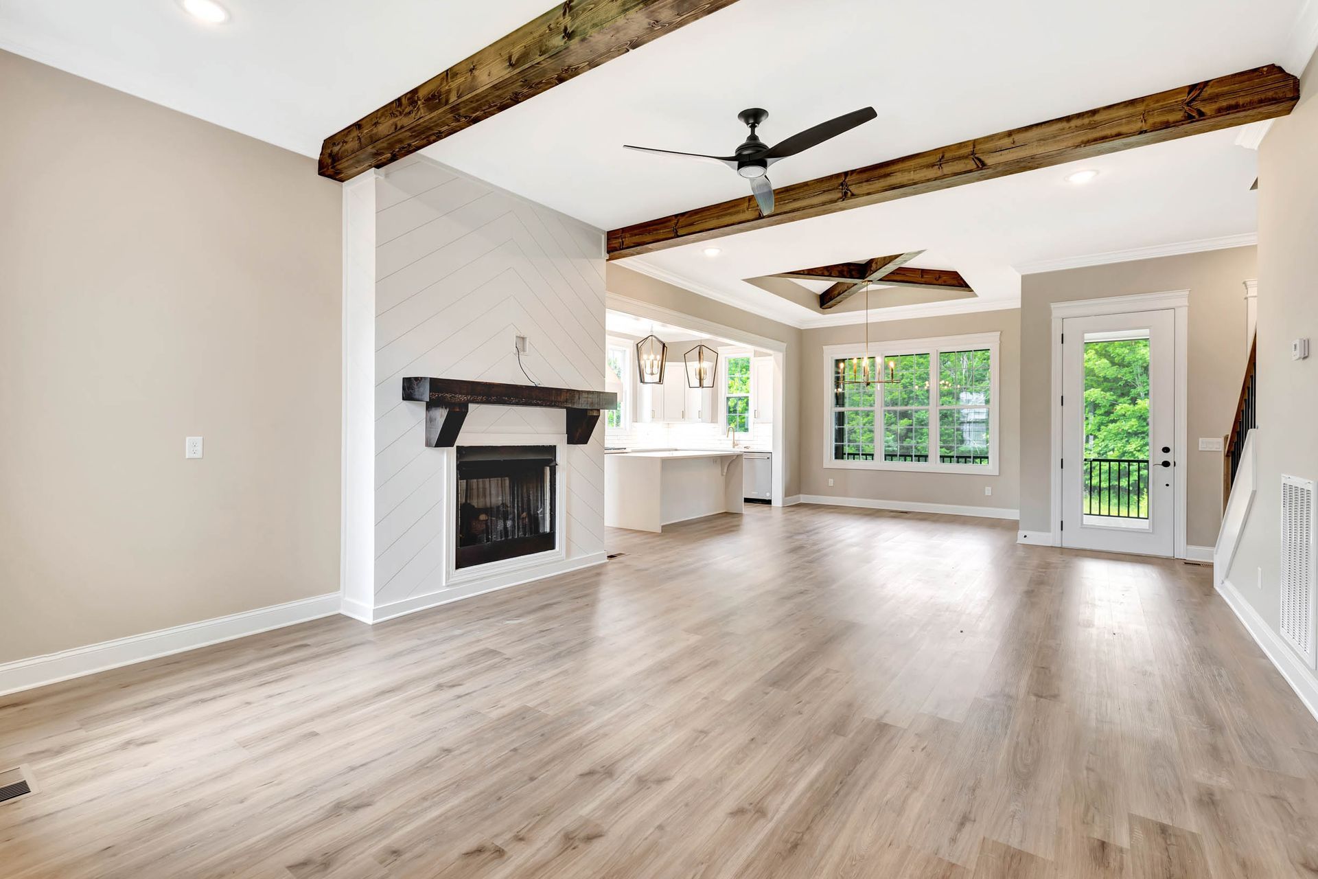 An empty living room with hardwood floors , a fireplace and a ceiling fan.