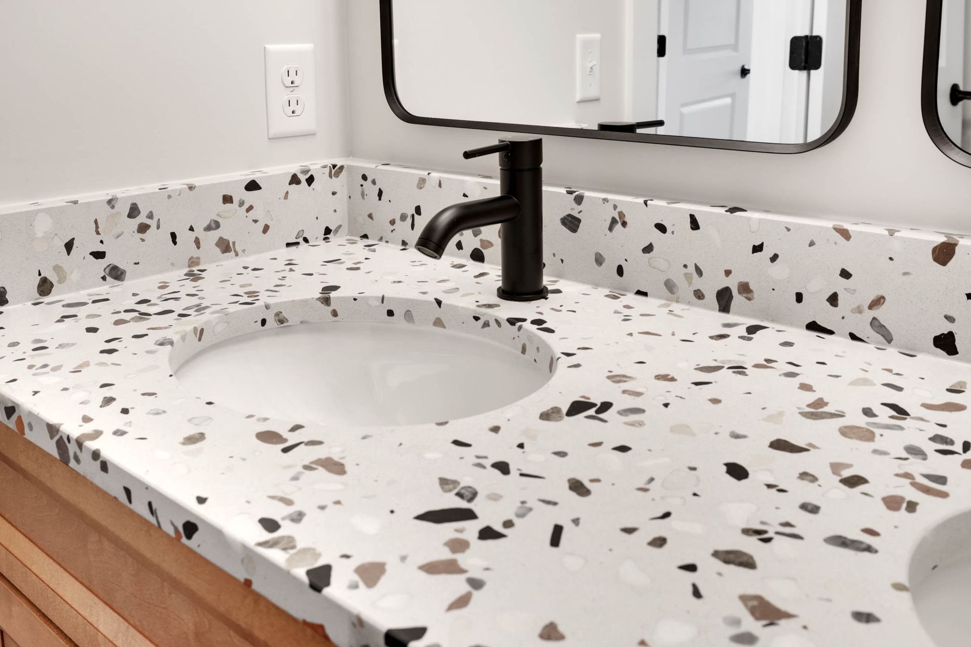 A bathroom sink with a black faucet and a mirror.