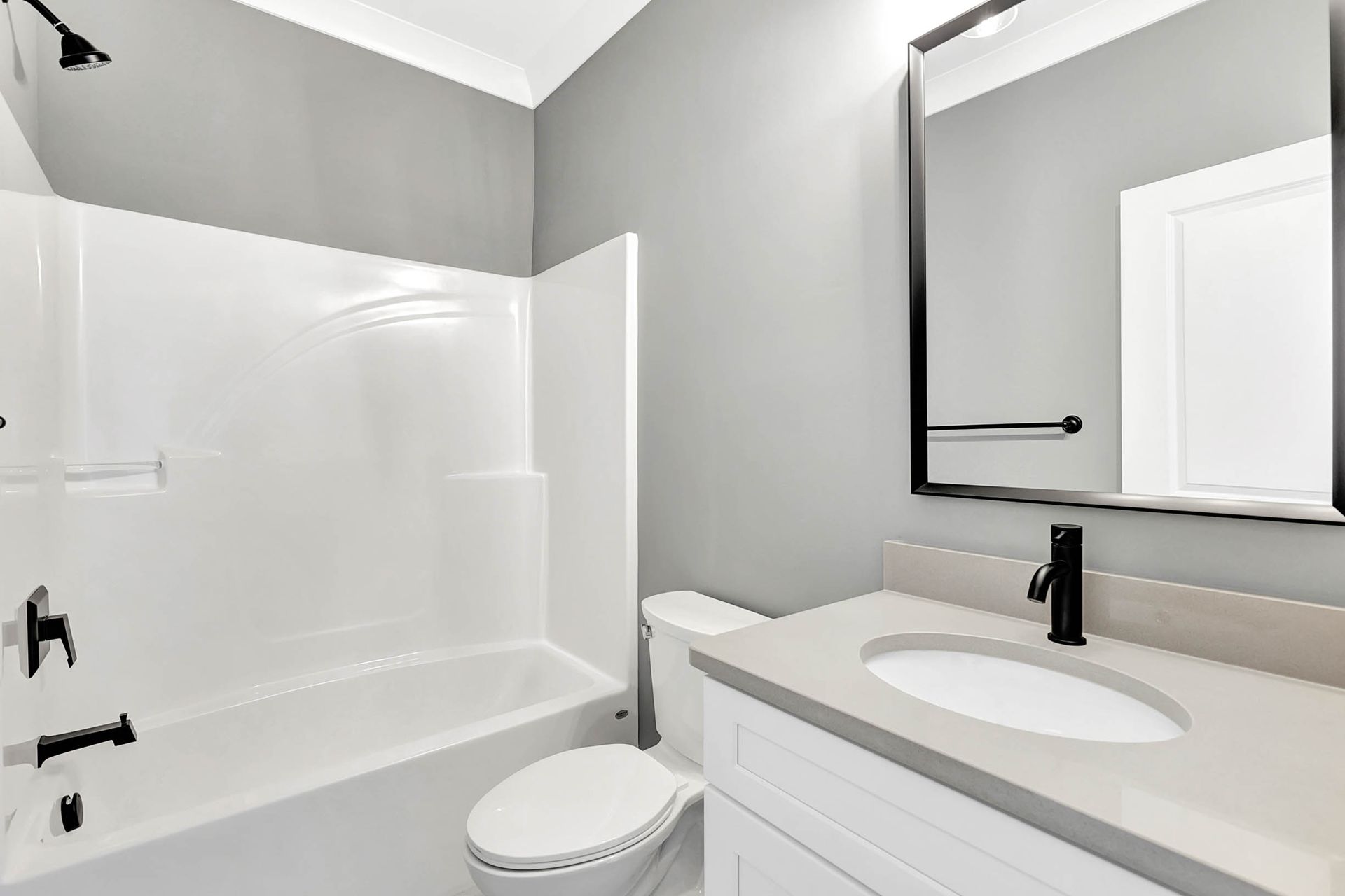 A bathroom with a toilet , sink , bathtub and mirror.