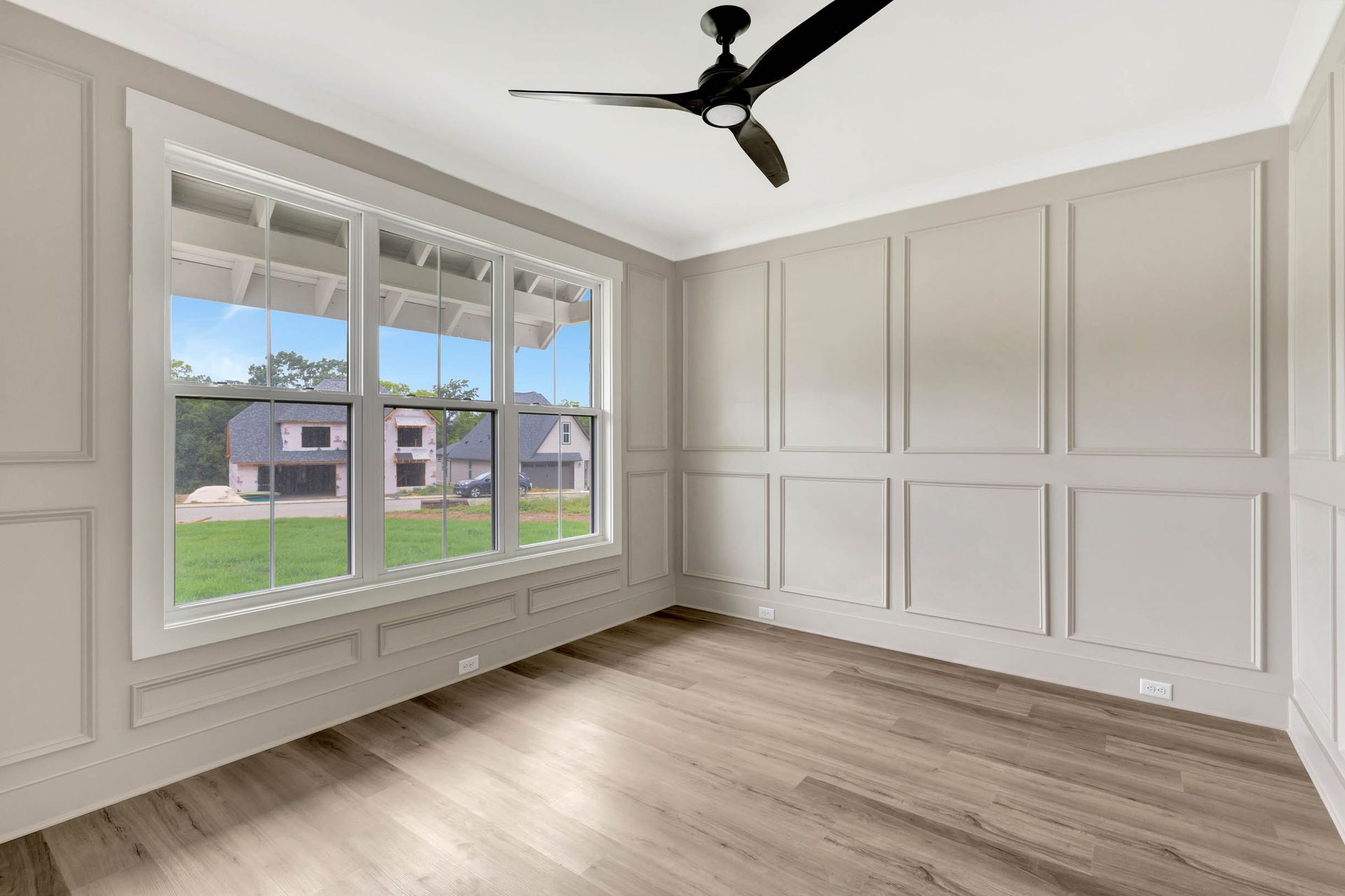 There is a ceiling fan in the room with a lot of windows.