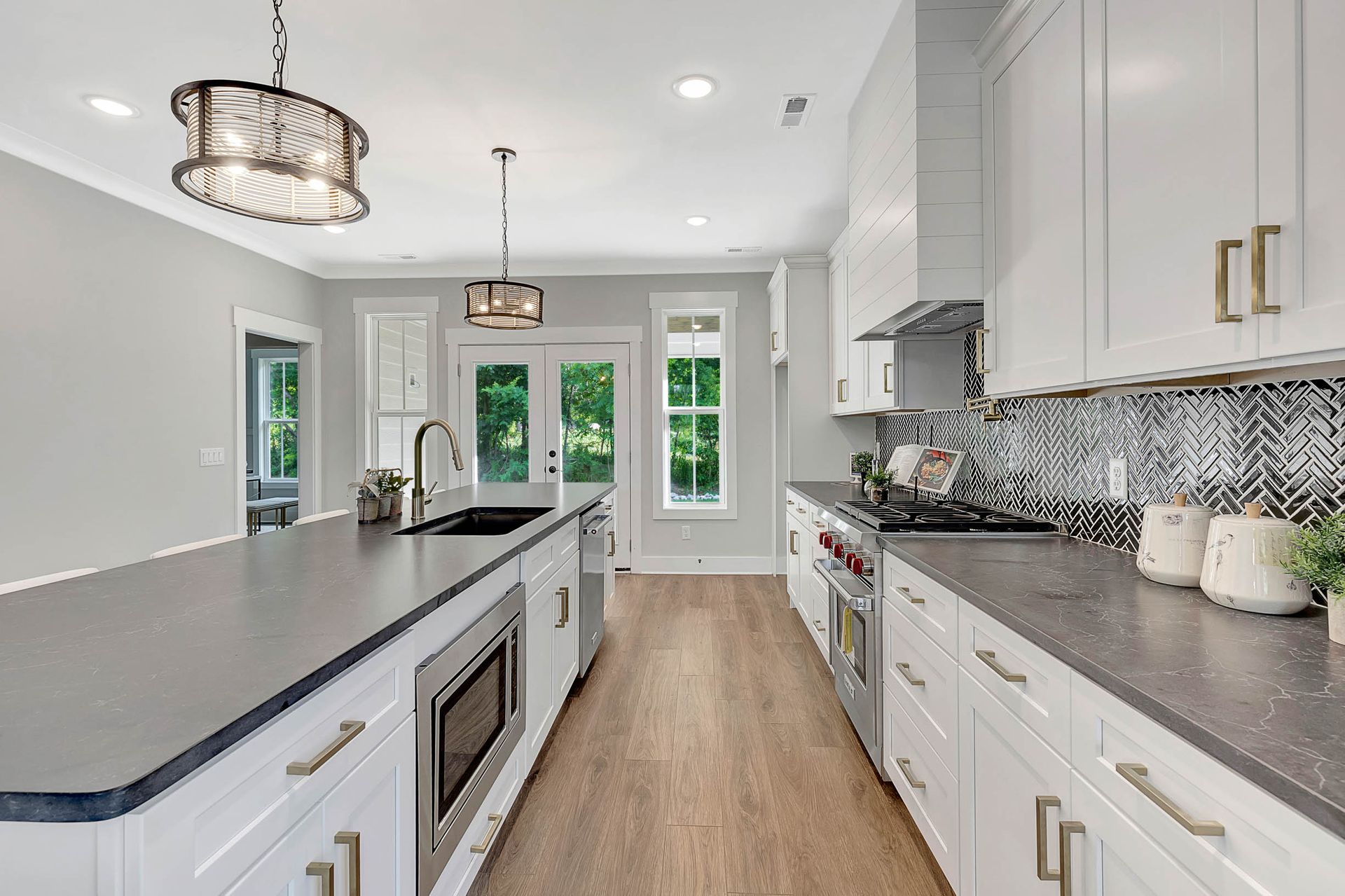 A kitchen with white cabinets , granite counter tops , stainless steel appliances and a large island.