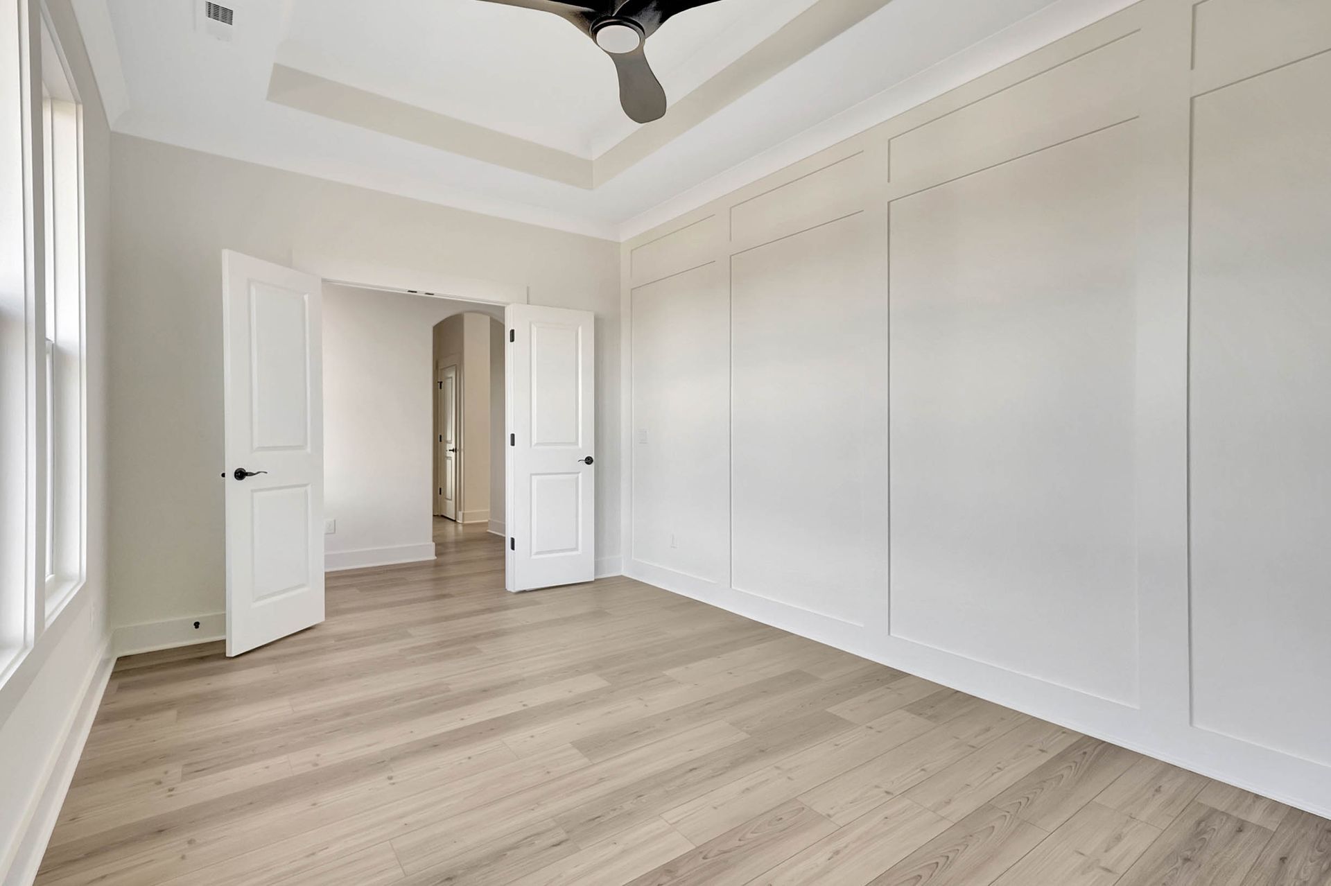 An empty bedroom with hardwood floors and a ceiling fan.
