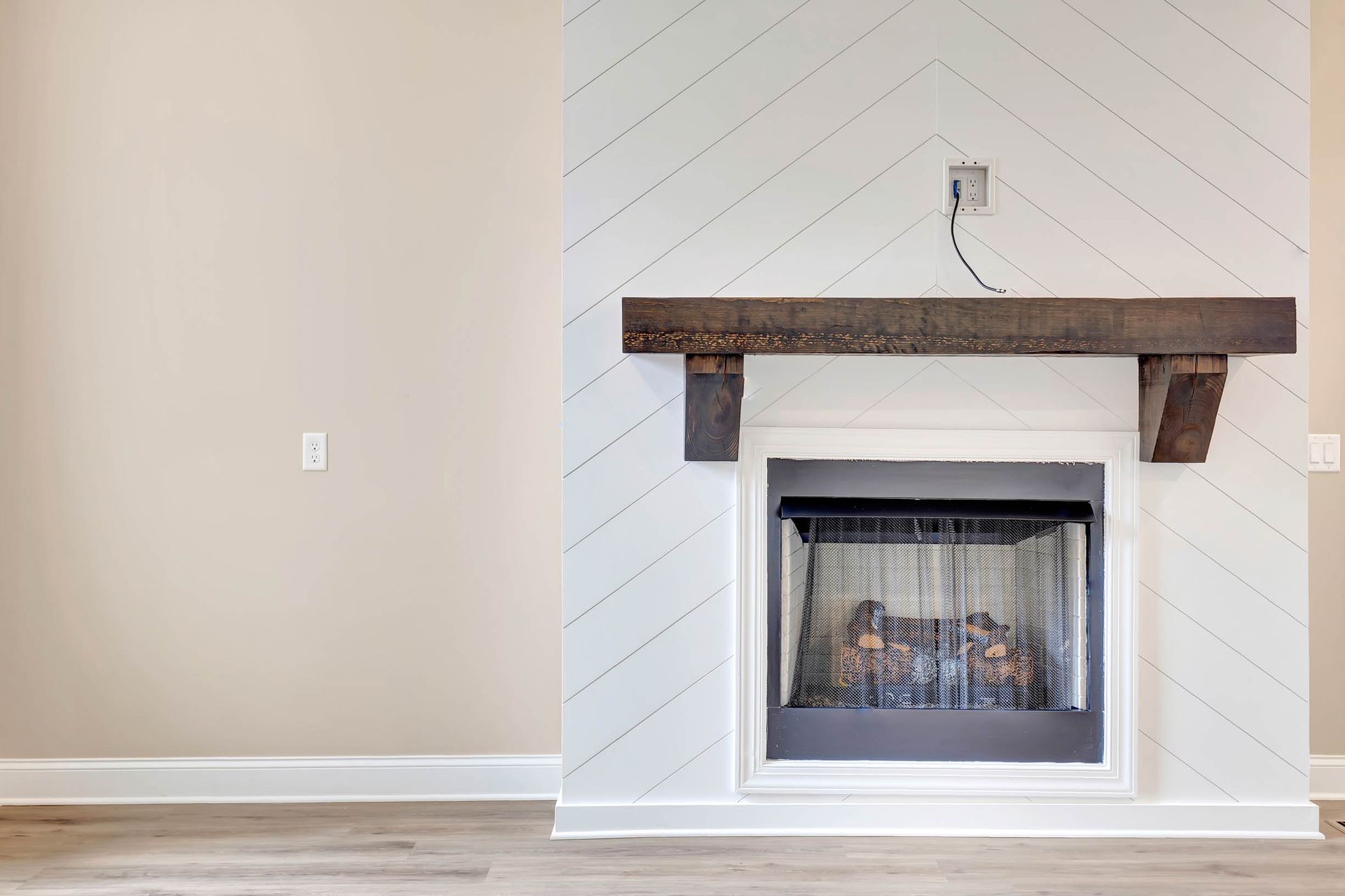 An empty living room with a fireplace and a wooden mantle.
