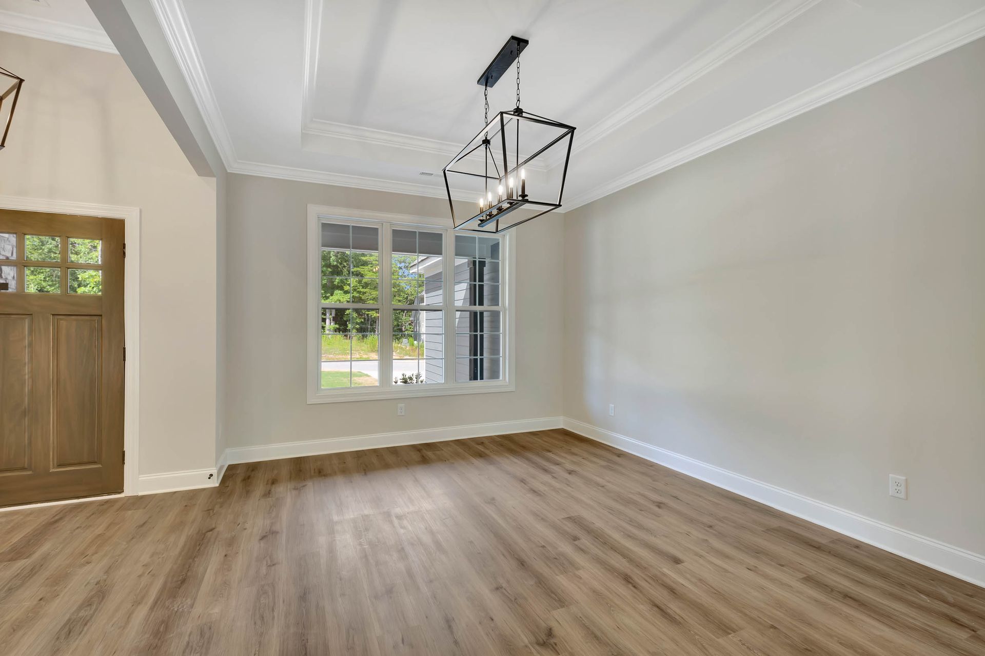 An empty living room with hardwood floors and a chandelier.