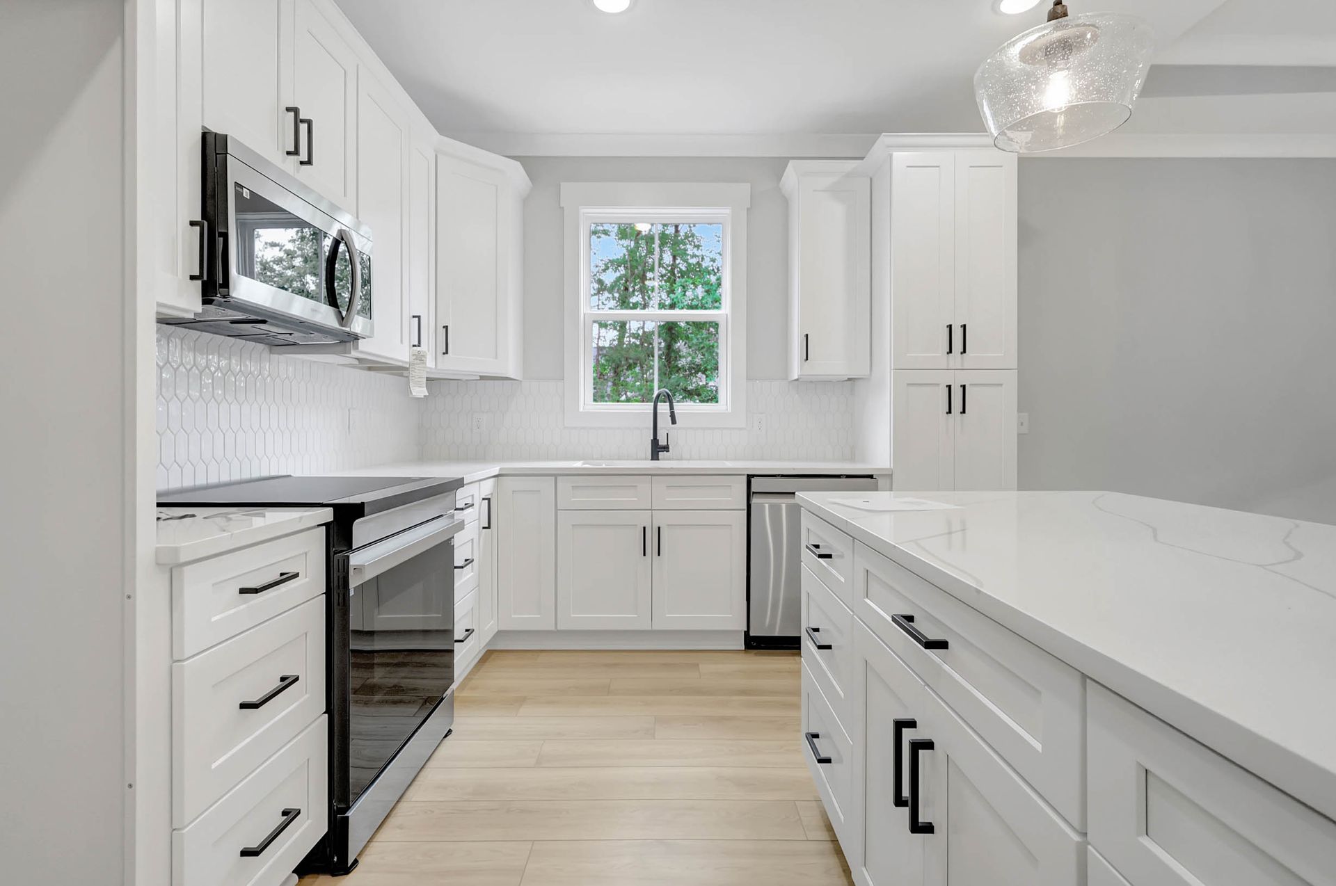 A kitchen with white cabinets , stainless steel appliances , and a large island.