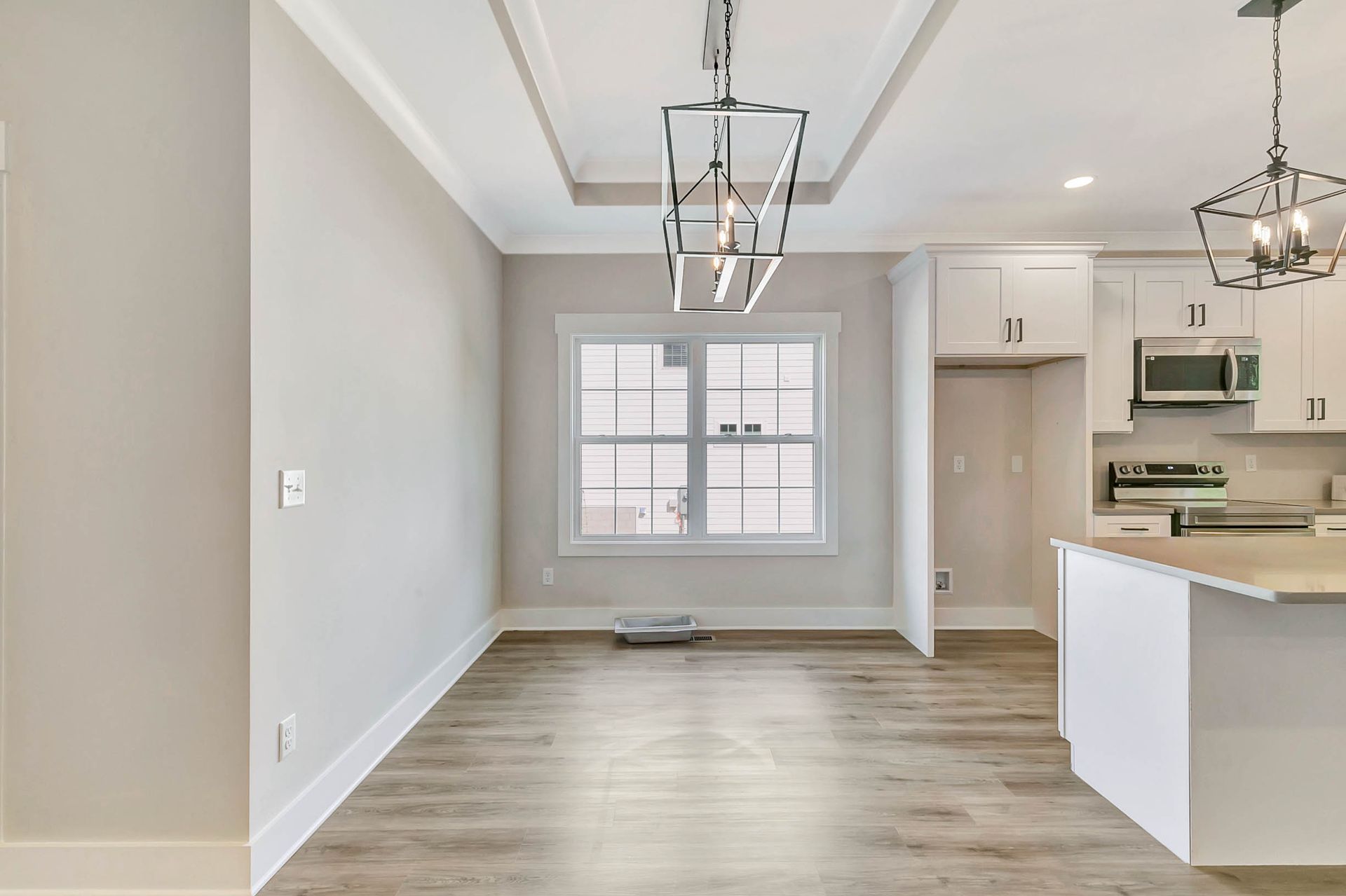 An empty living room with a kitchen in the background