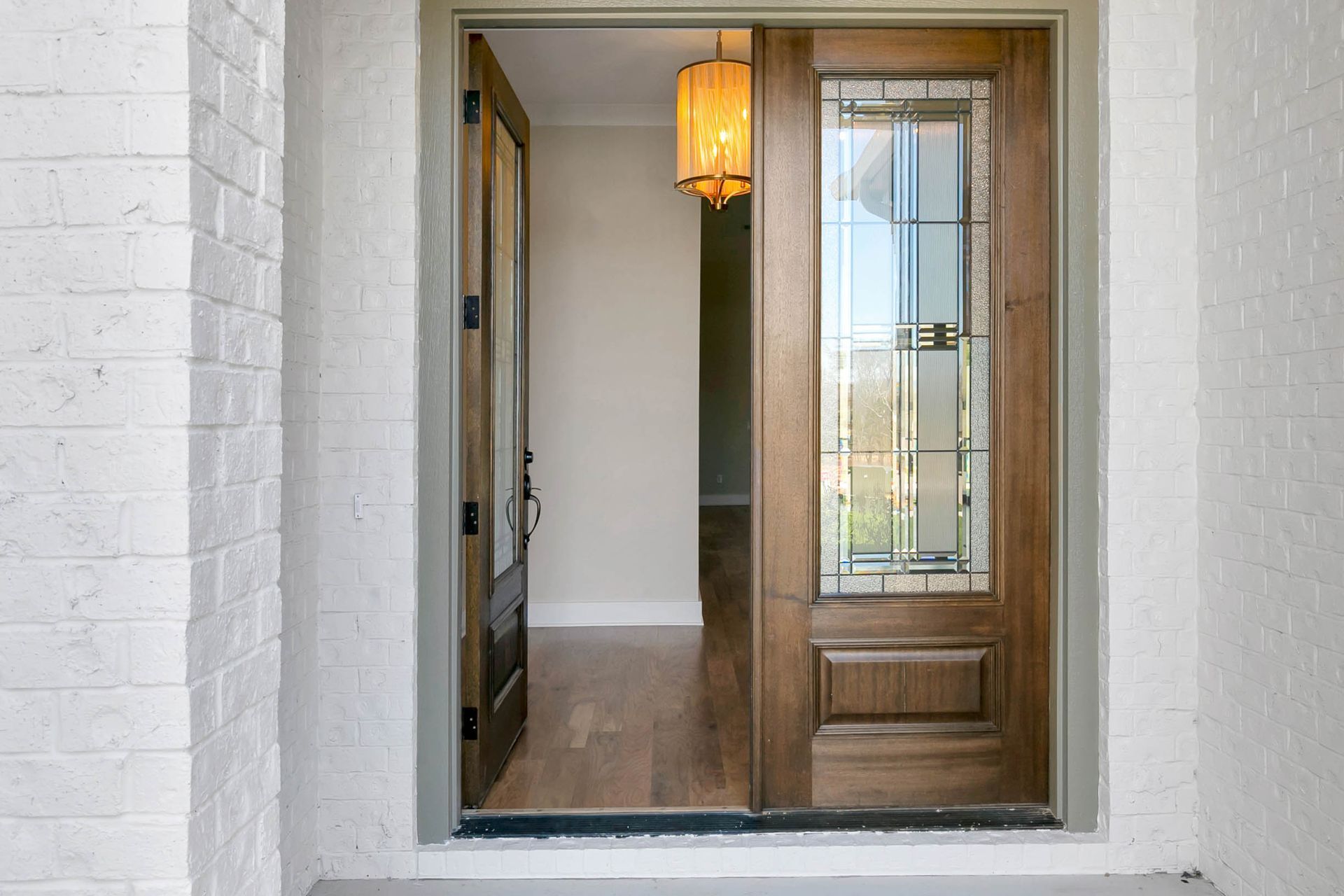 A wooden door with a glass window is open to a hallway.