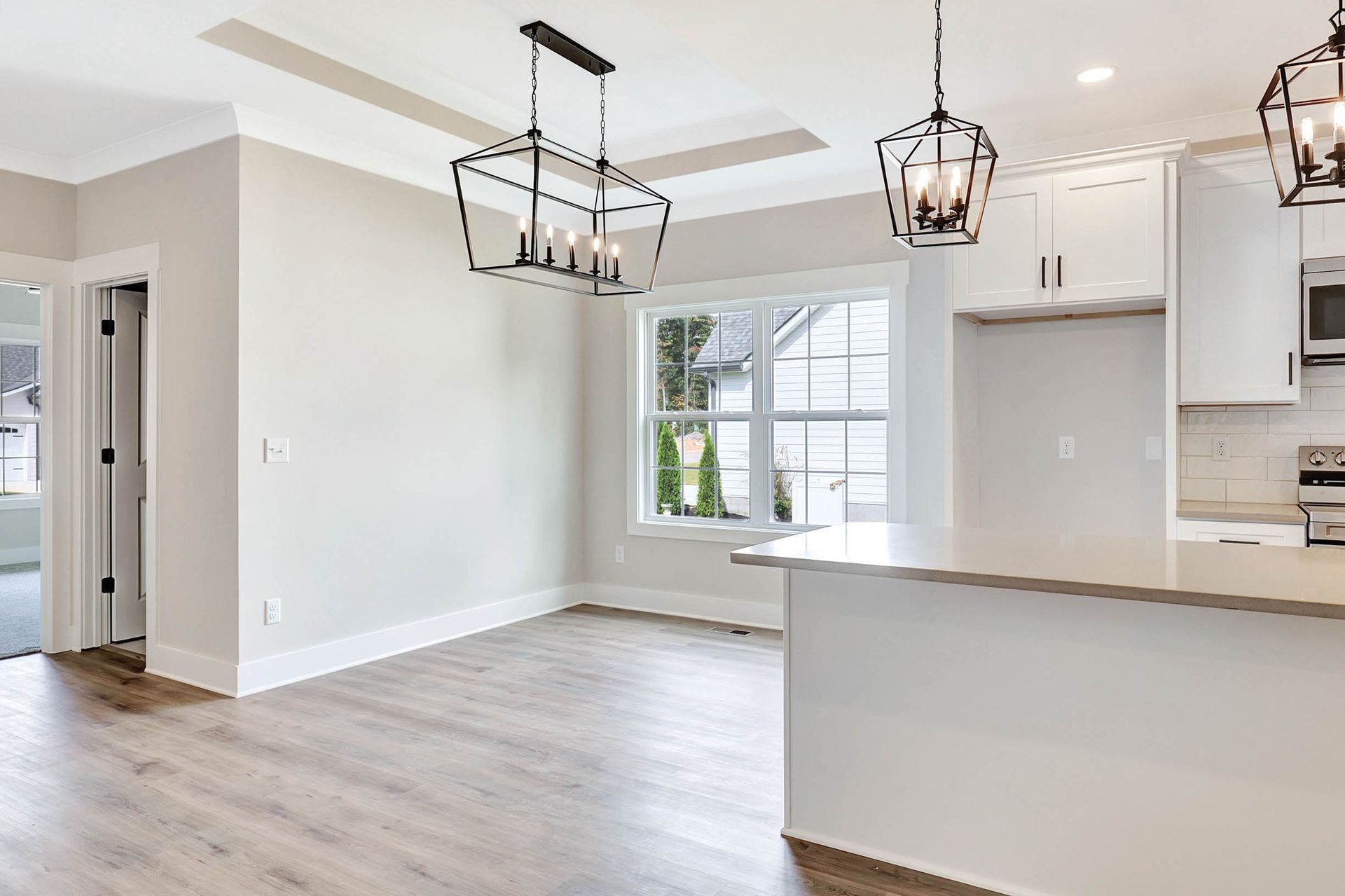 A kitchen and living room in a house with hardwood floors and white cabinets.