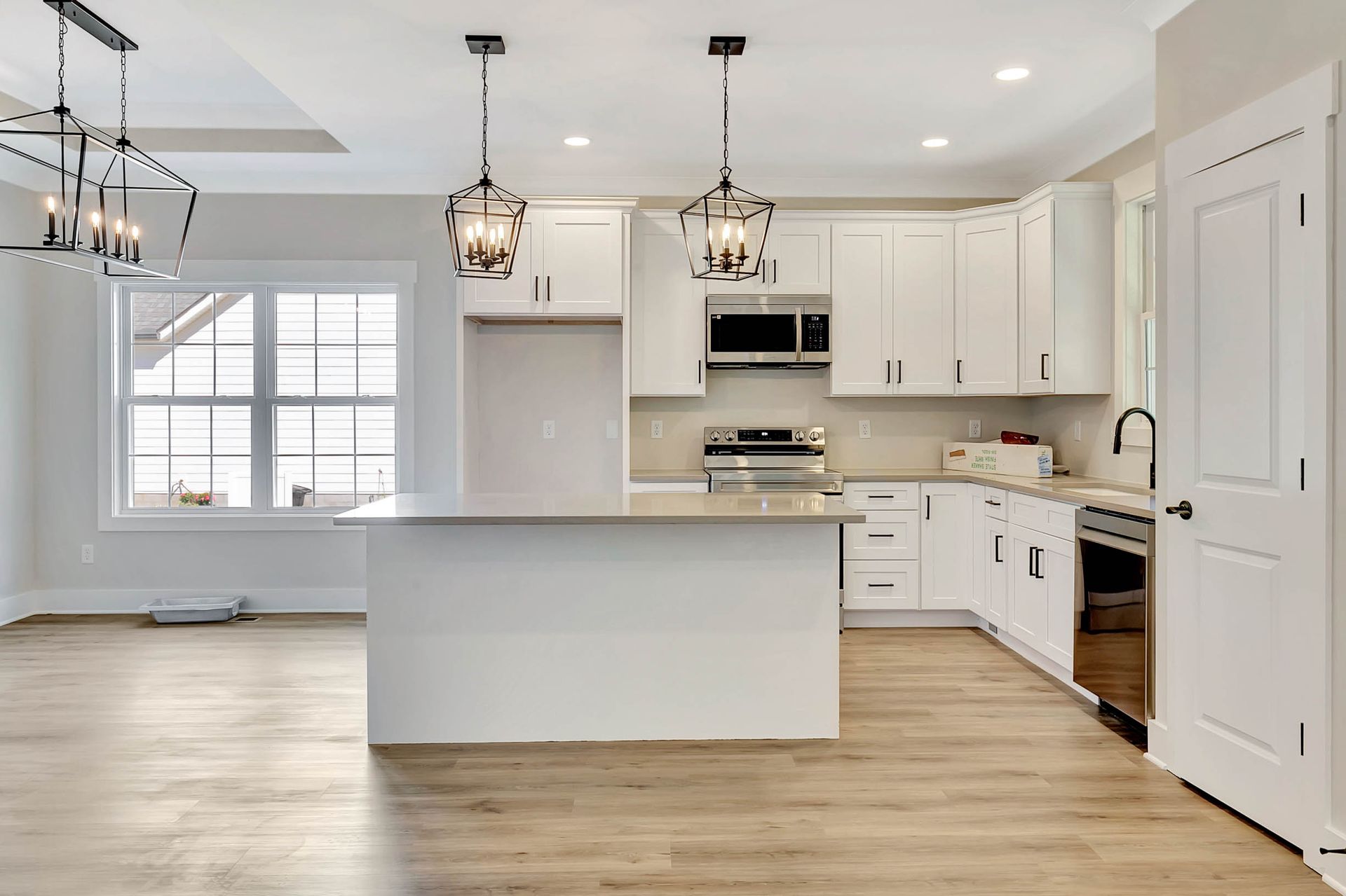 An empty kitchen with white cabinets and stainless steel appliances