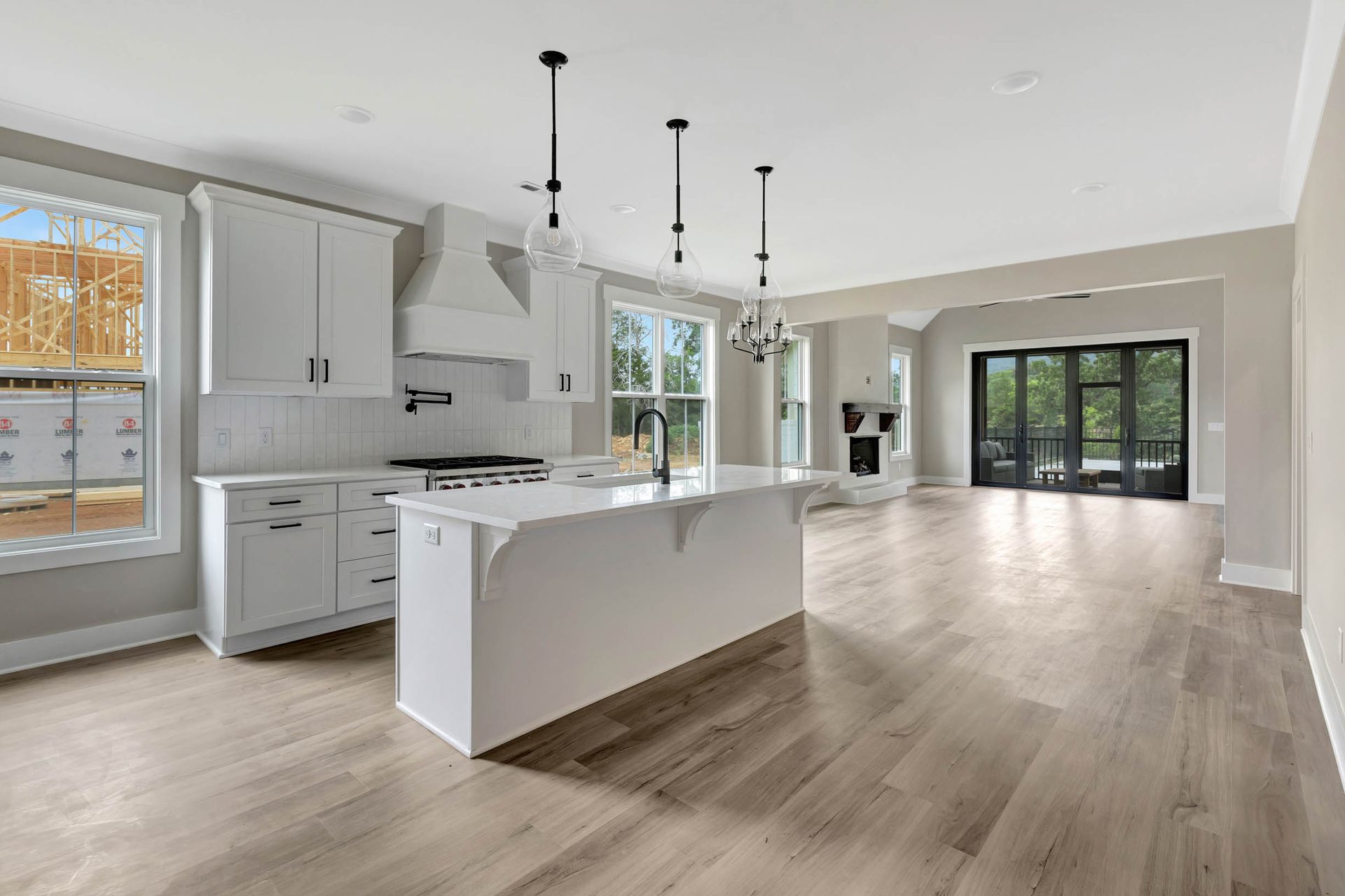 A kitchen in a new home with white cabinets and hardwood floors.