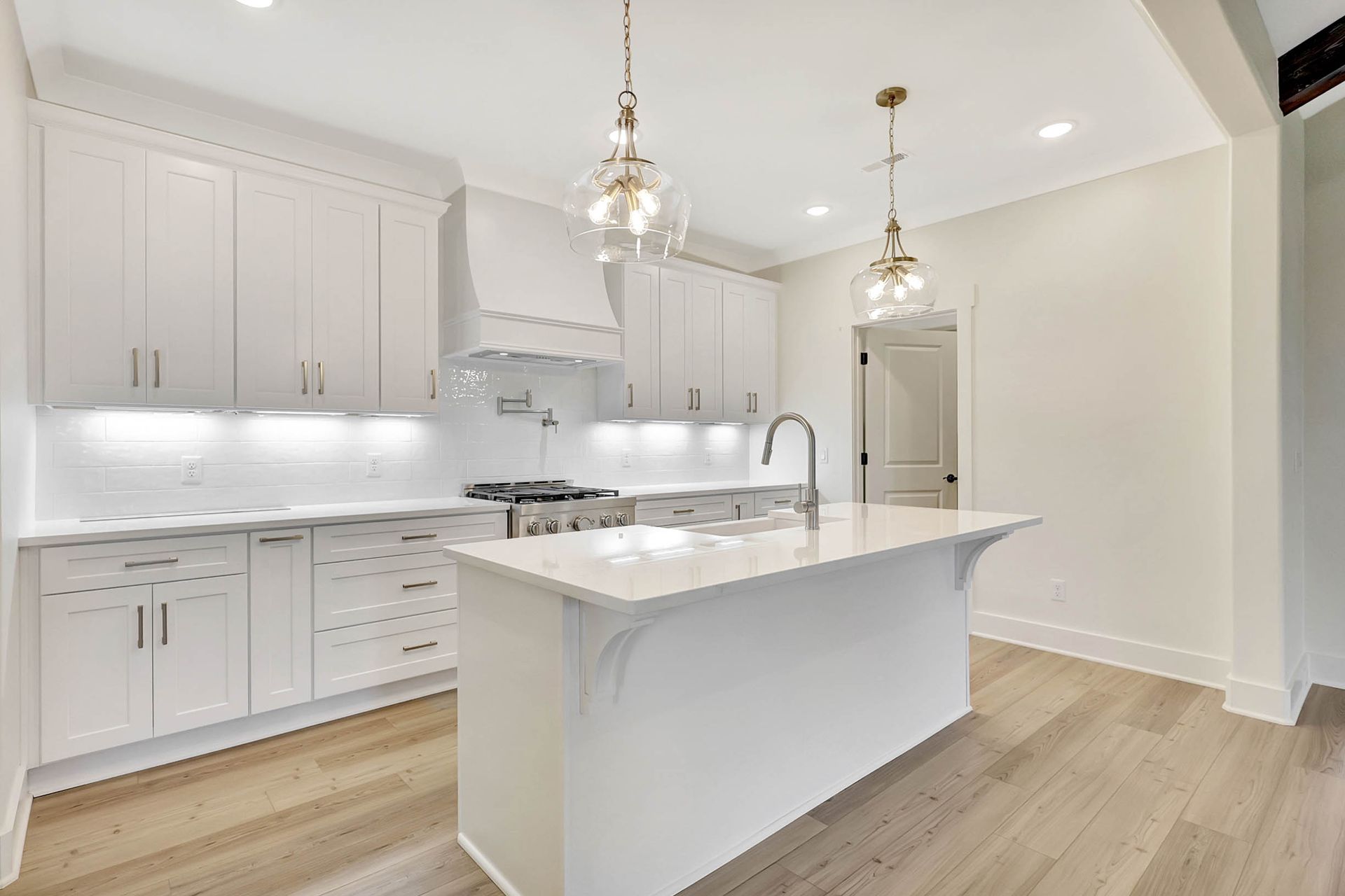 A kitchen with white cabinets and a large island in the middle.
