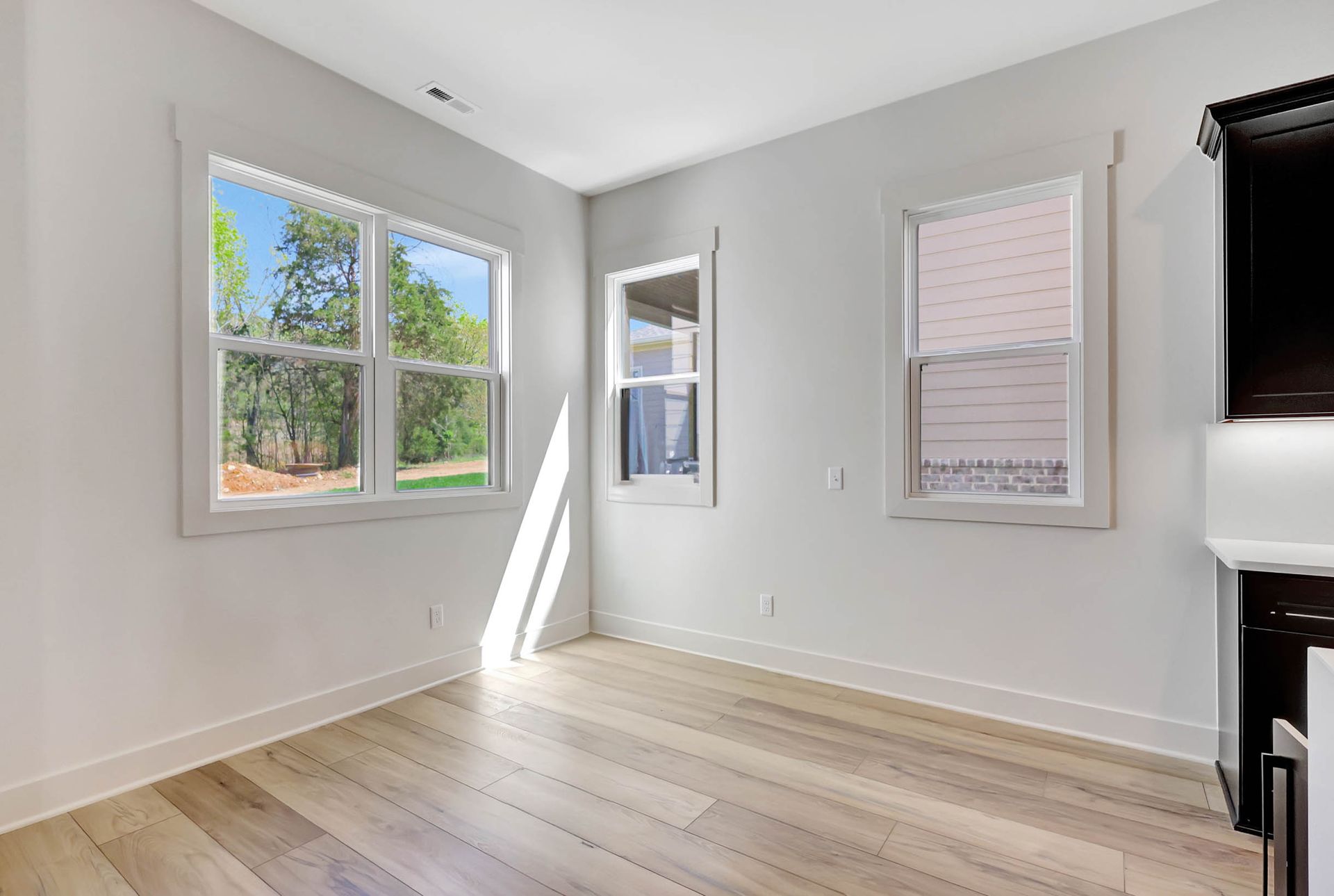An empty room with hardwood floors and two windows.