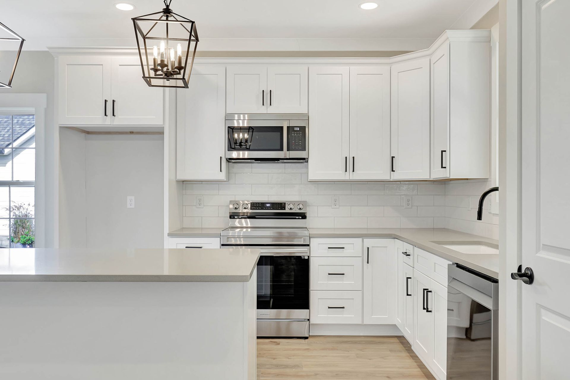 A kitchen with white cabinets , stainless steel appliances , and a large island.