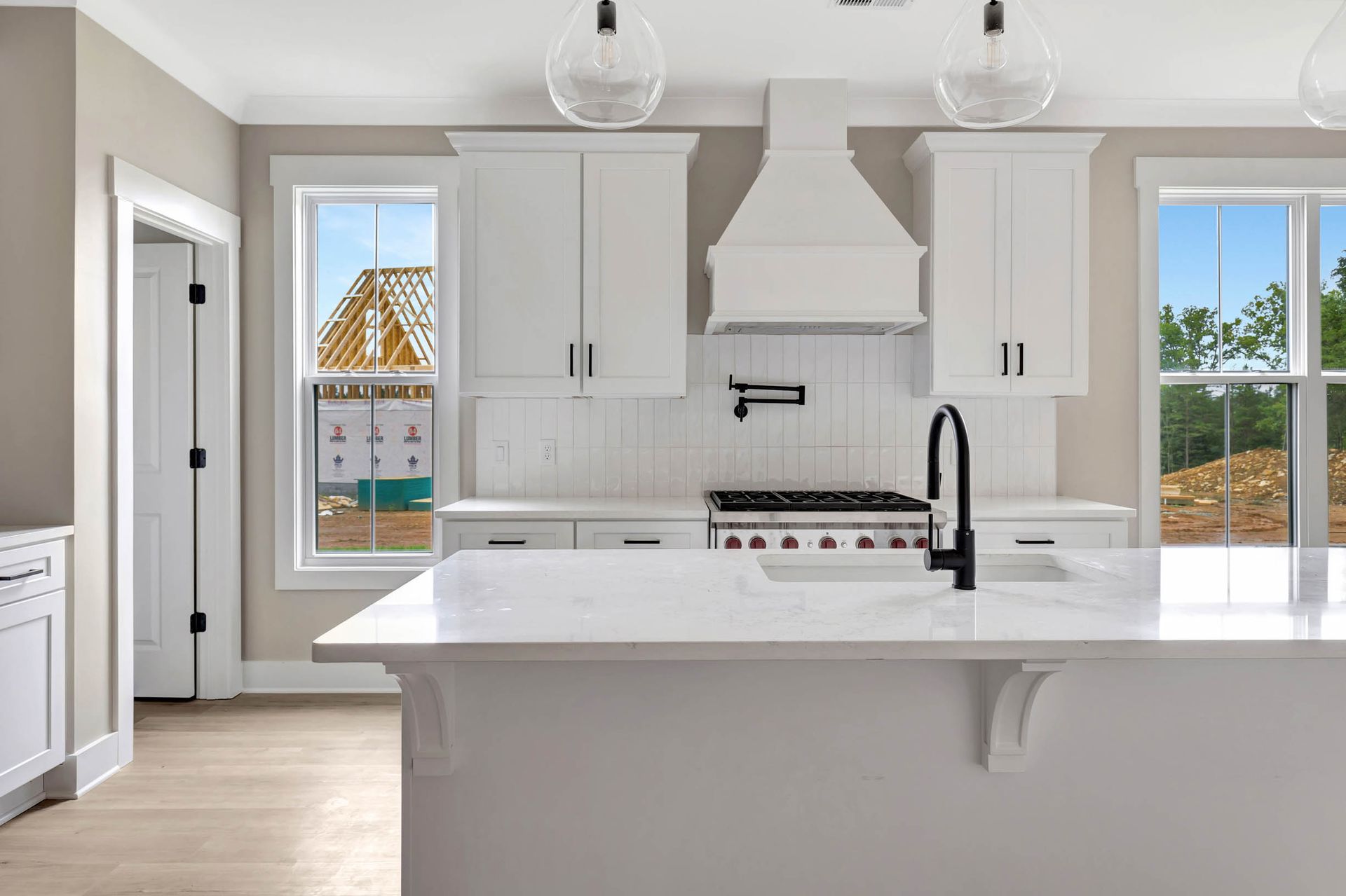 A kitchen with white cabinets , a stove , a sink , and a large island.