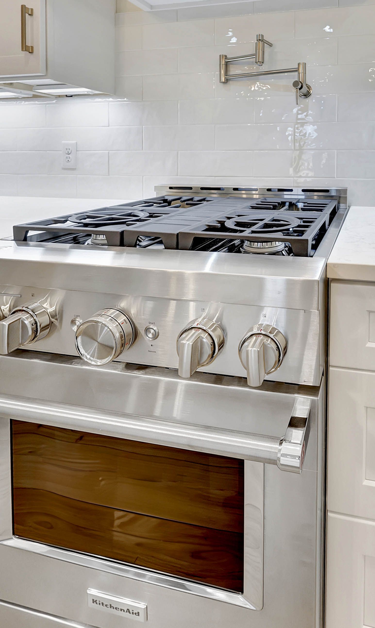 A stainless steel stove with a wooden door is in a kitchen.
