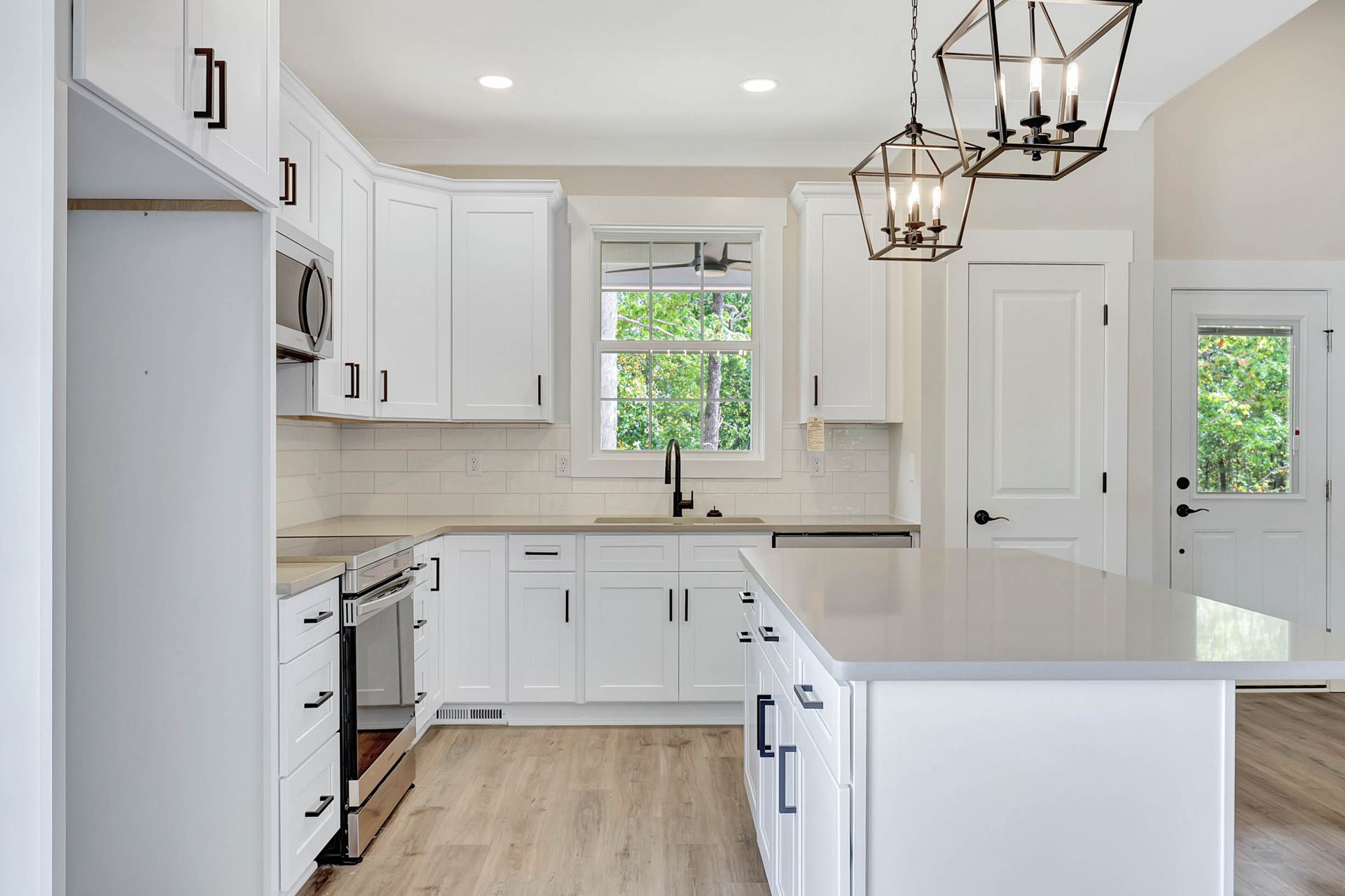 A kitchen with white cabinets , stainless steel appliances , and a large island.