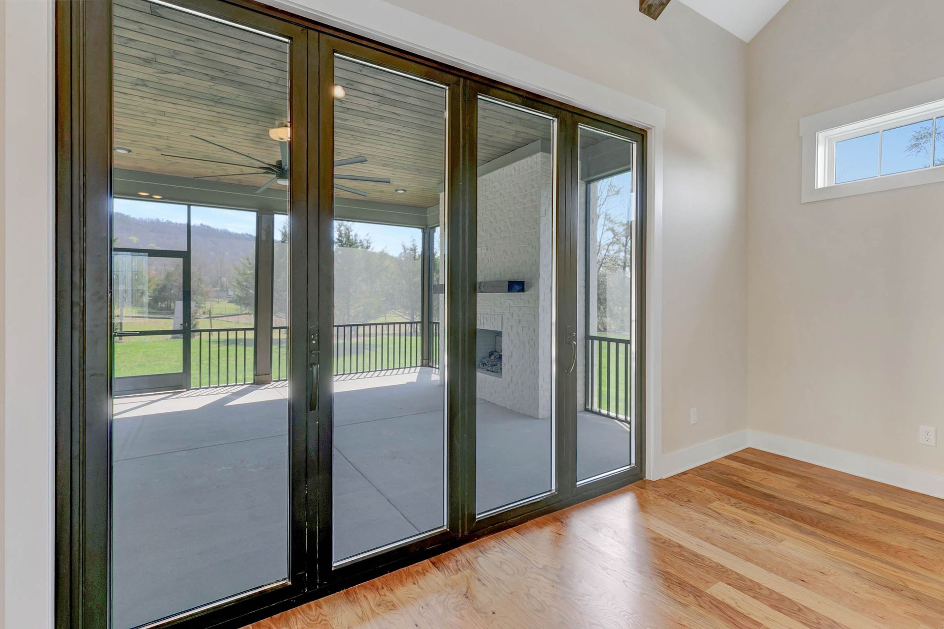 An empty room with sliding glass doors leading to a screened in porch.